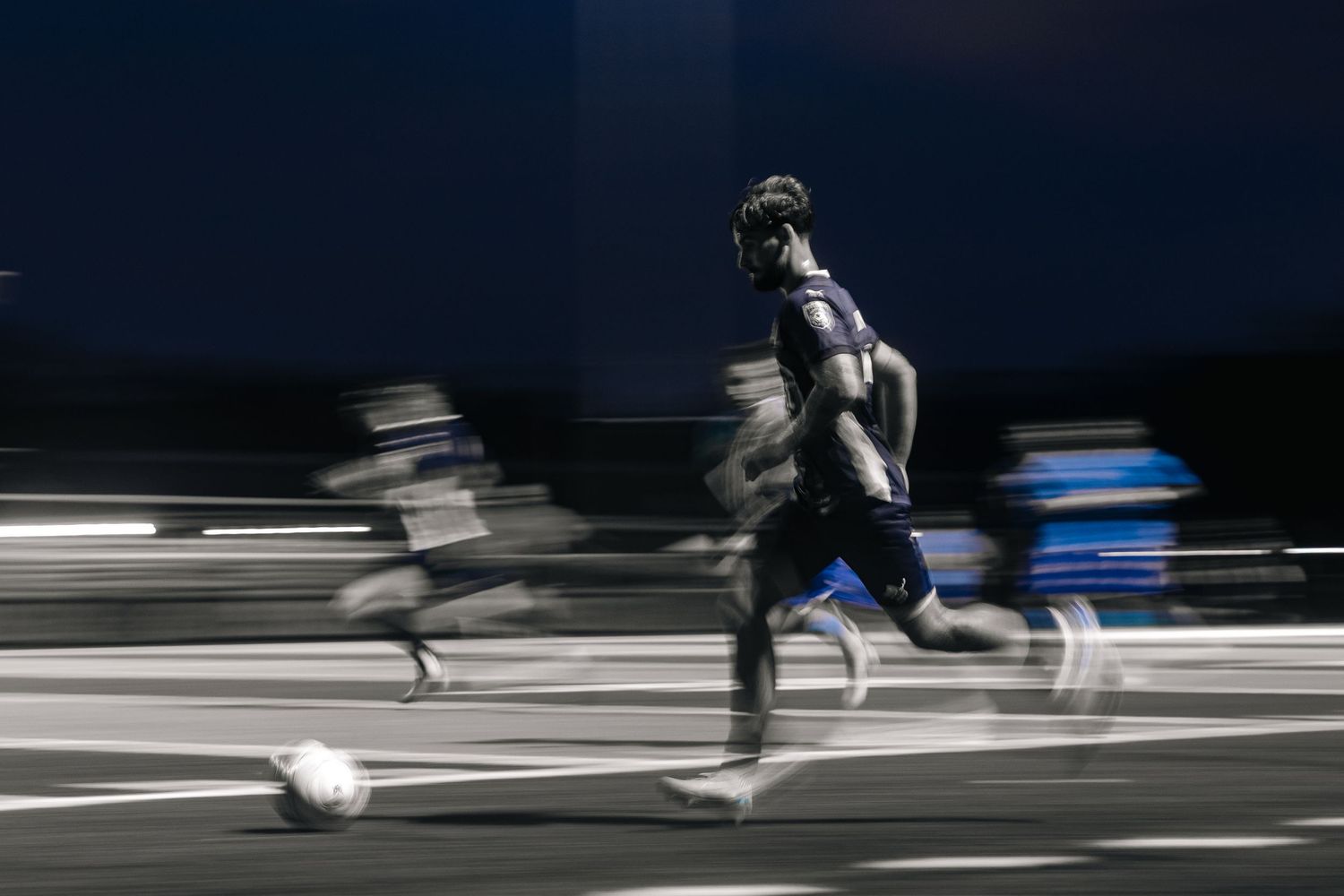 Motion blur of athletes running on a dark track with dramatic lighting.