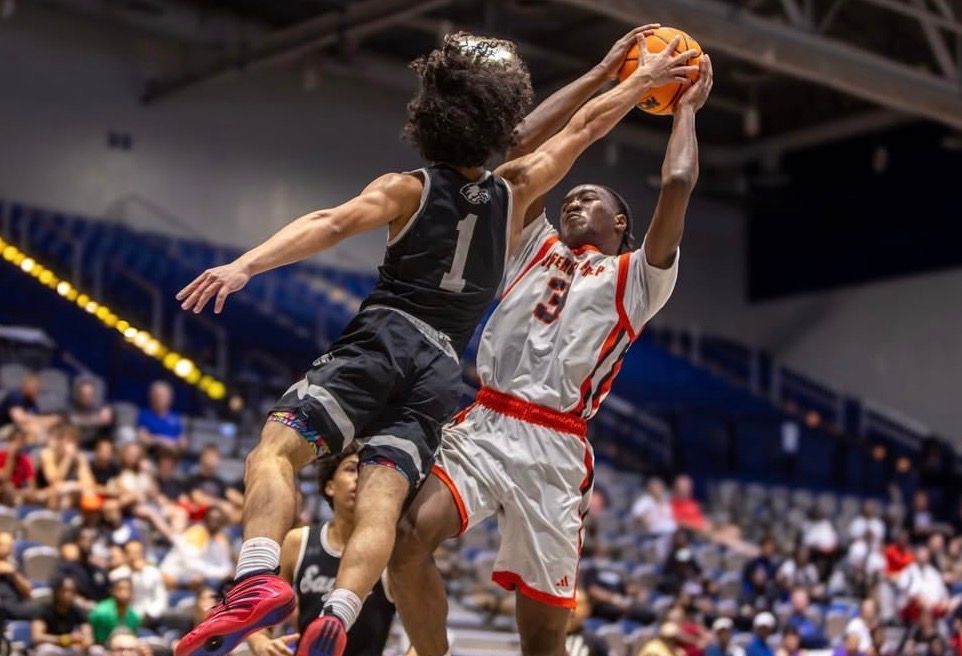 Basketball players jumping for rebound during intense game action in arena.