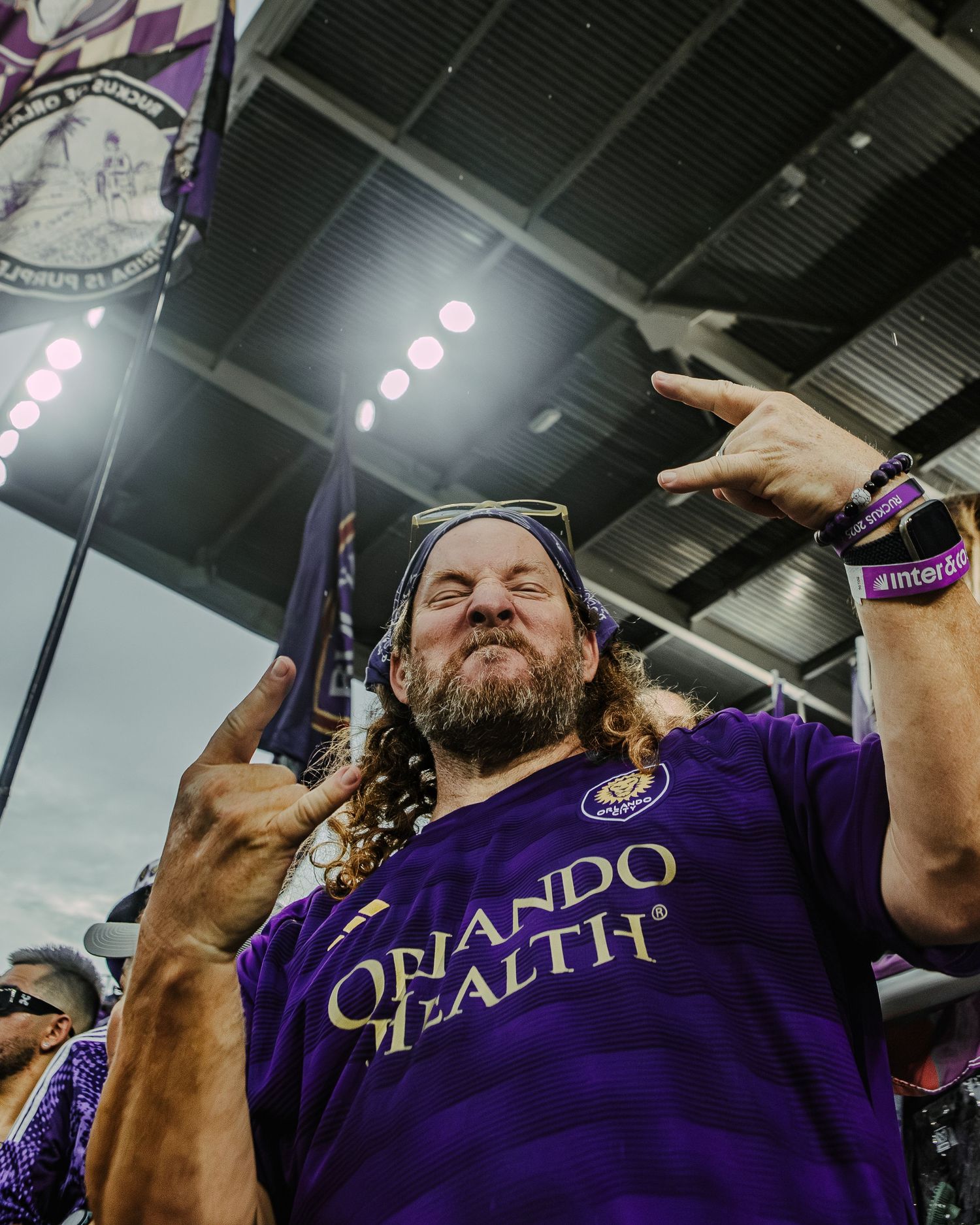 Soccer supporters in purple jerseys celebrate at a sporting event.