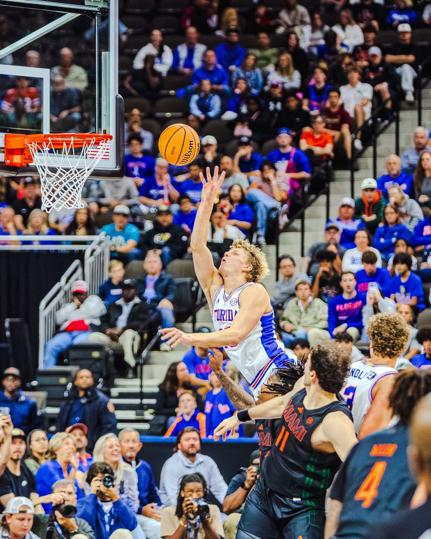 Basketball player leaps for layup during intense game action.