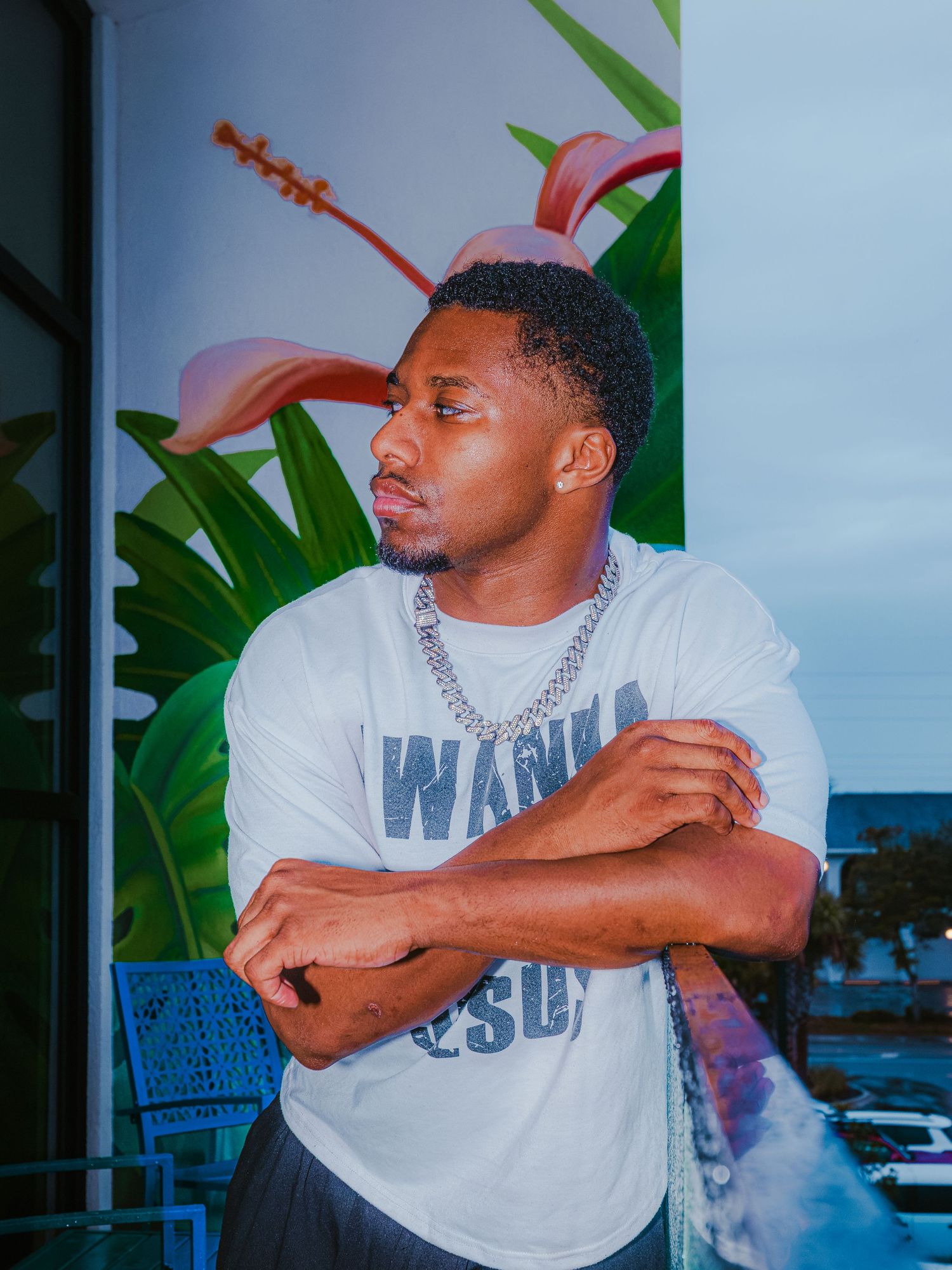 Casual outdoor photoshoot with tropical plants and blue sky in the background.