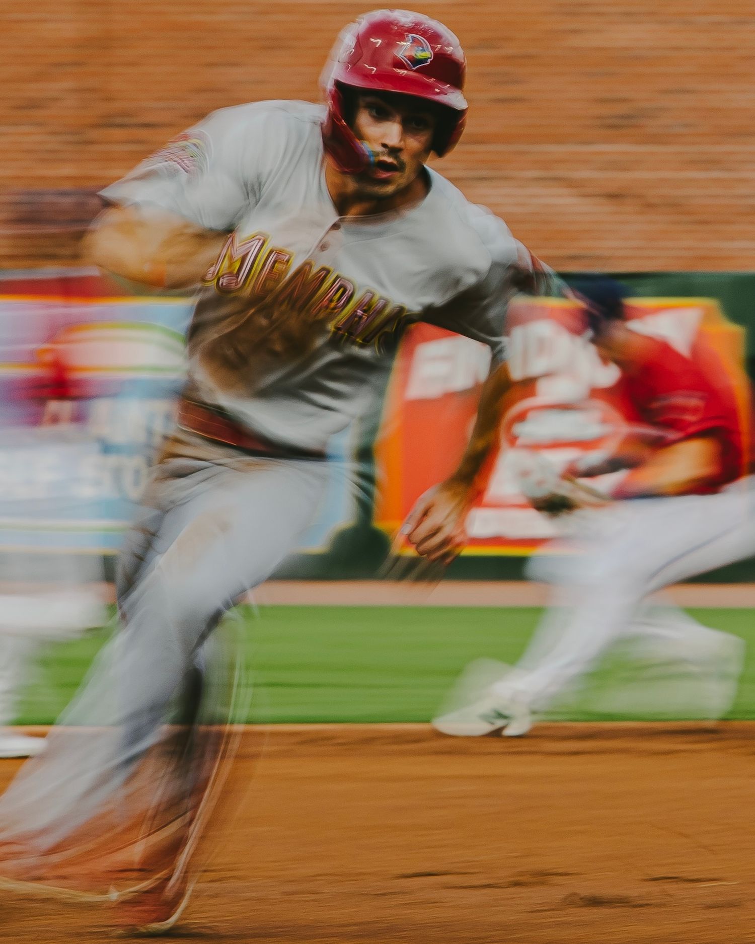 Motion blur of baseball players running on field in grey uniforms.