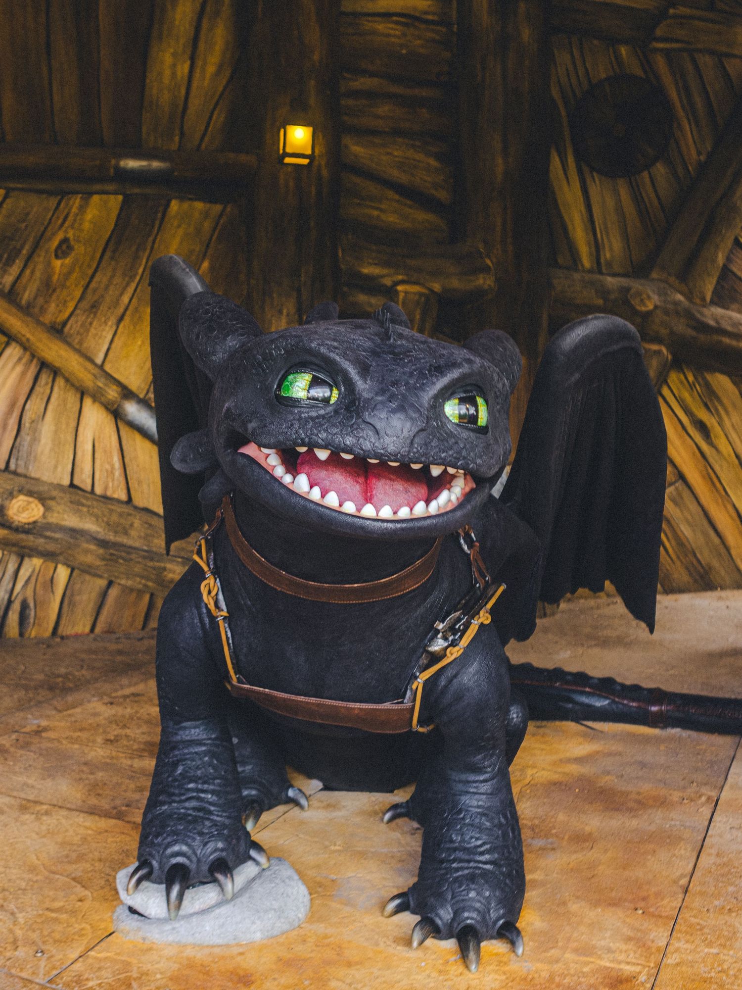 Black plush dragon toy with glowing eyes and teeth displayed on wooden floor.