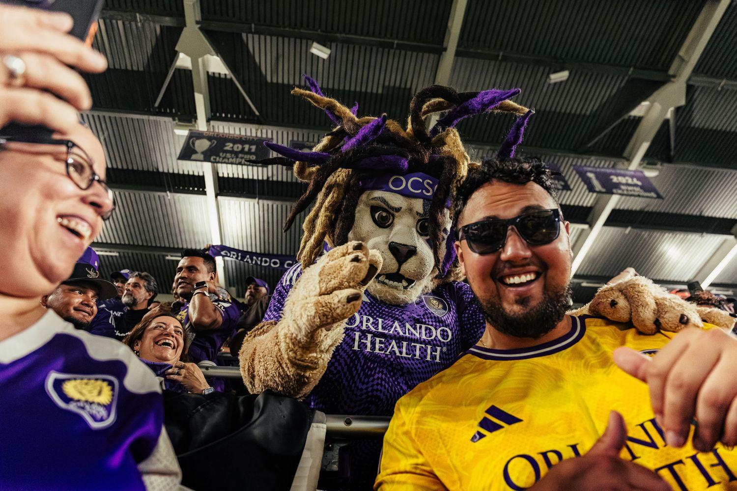 Sports supporters wearing team merchandise celebrating together at an indoor arena.