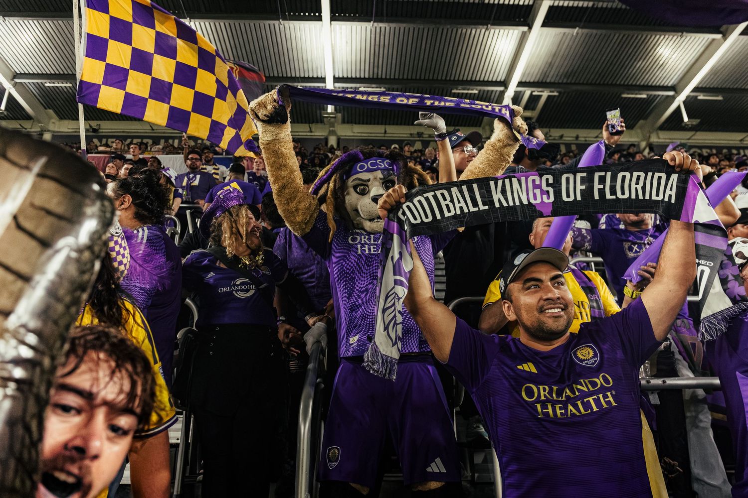Crowd of sports fans cheering in purple jerseys at an indoor stadium event.