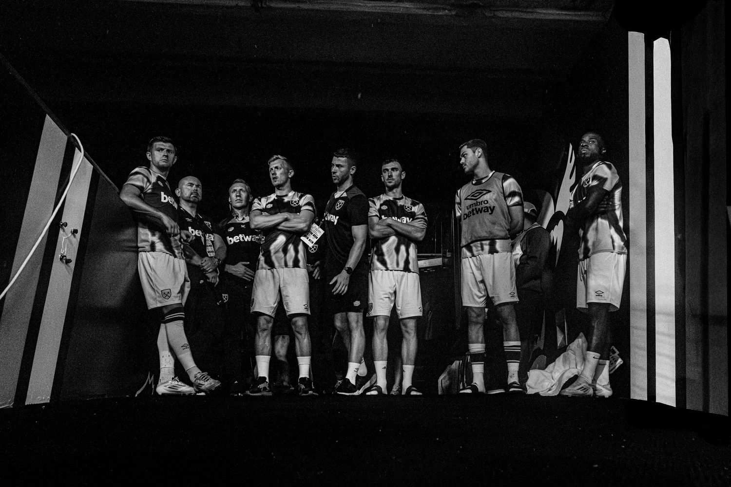 Team huddle of athletes in black and white uniforms shown in monochrome.