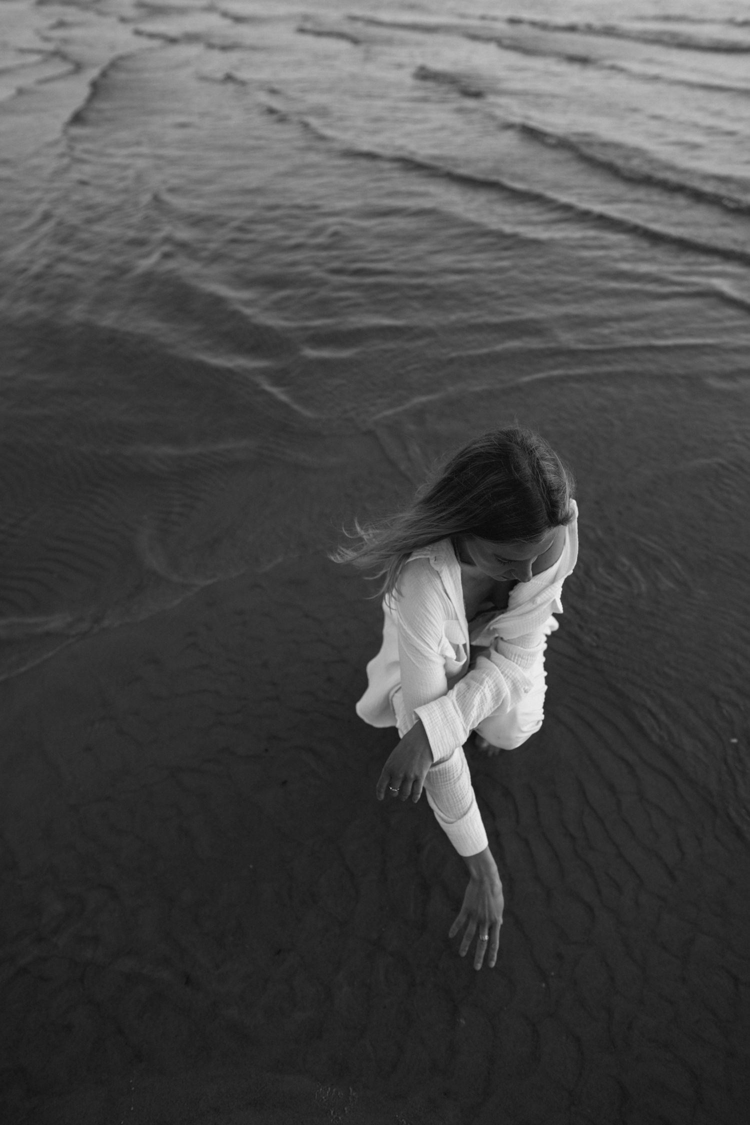 Woman standing in shallow water viewed from above with gentle ripples.