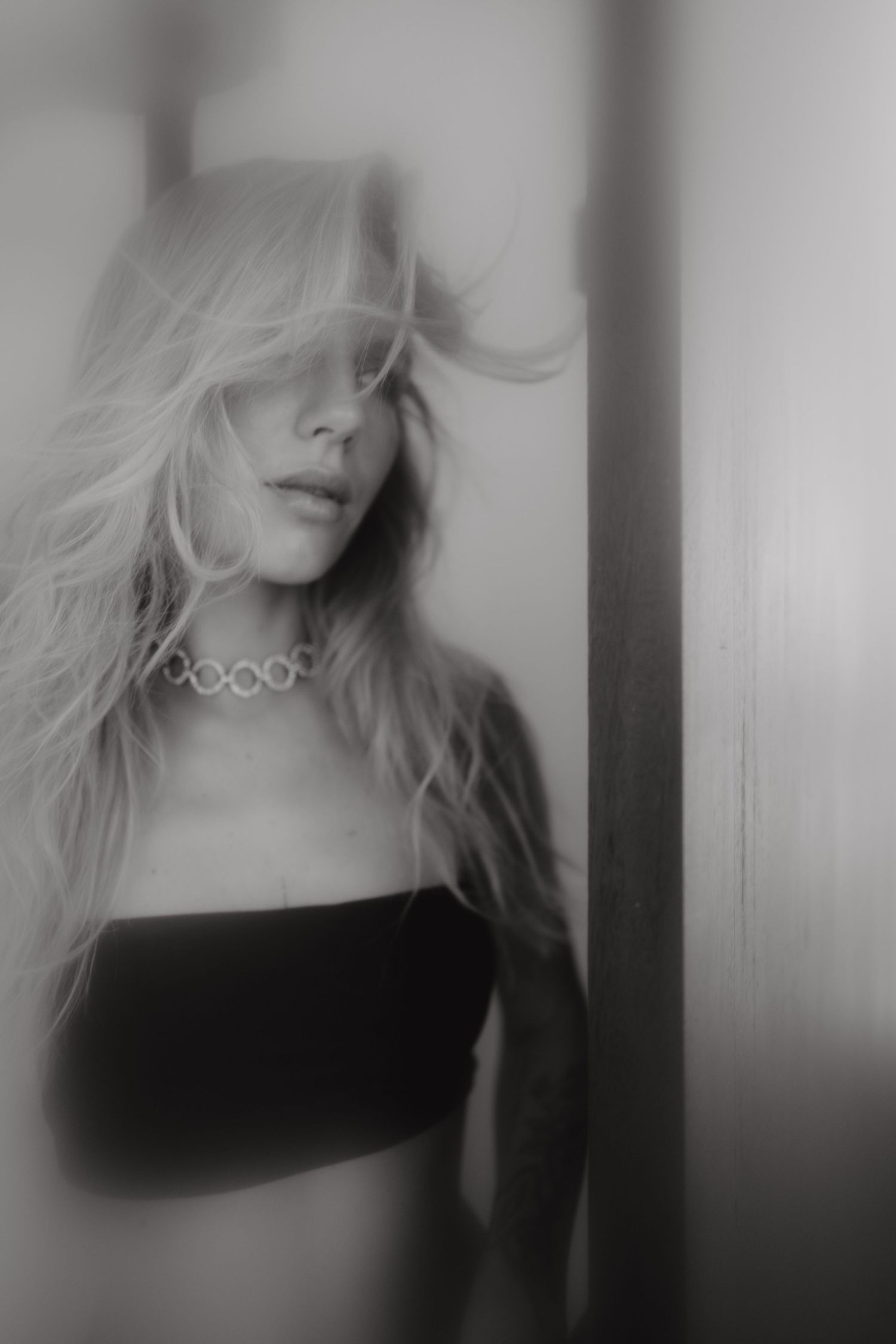 Black and white portrait of woman with windblown hair and soft motion blur.
