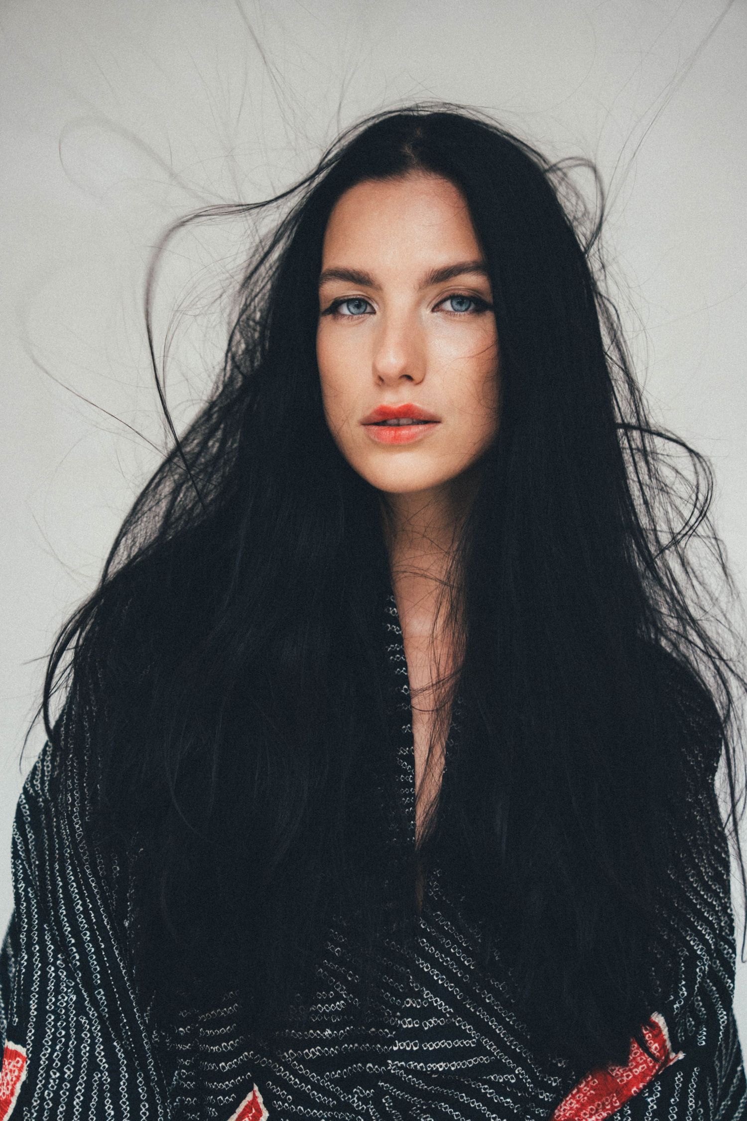 Close-up portrait of woman with long dark hair against neutral background.