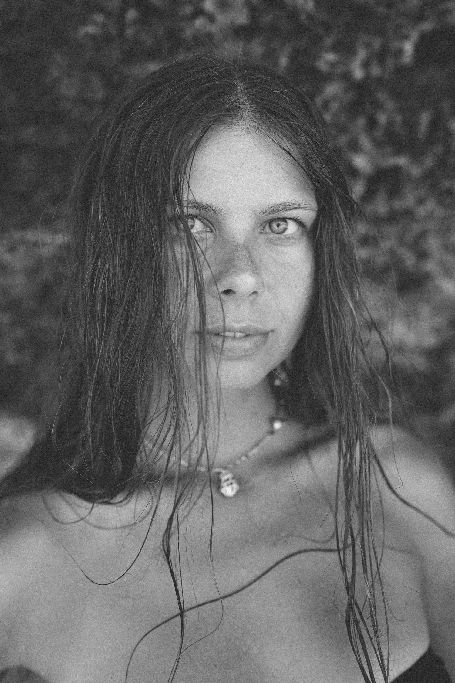 Black and white close-up portrait of woman with wet hair and direct gaze.