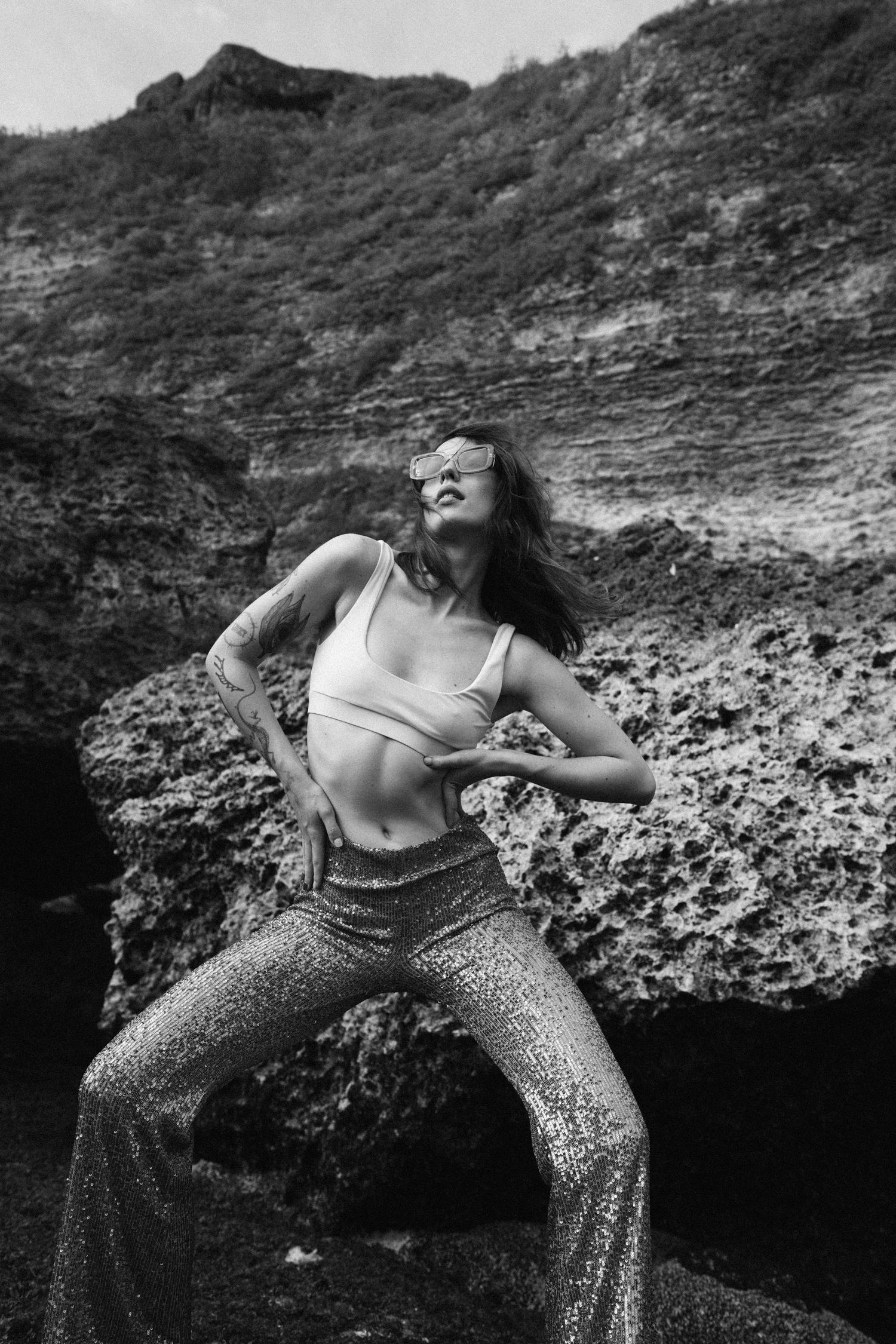 Black and white portrait of woman posing against textured rock formation.