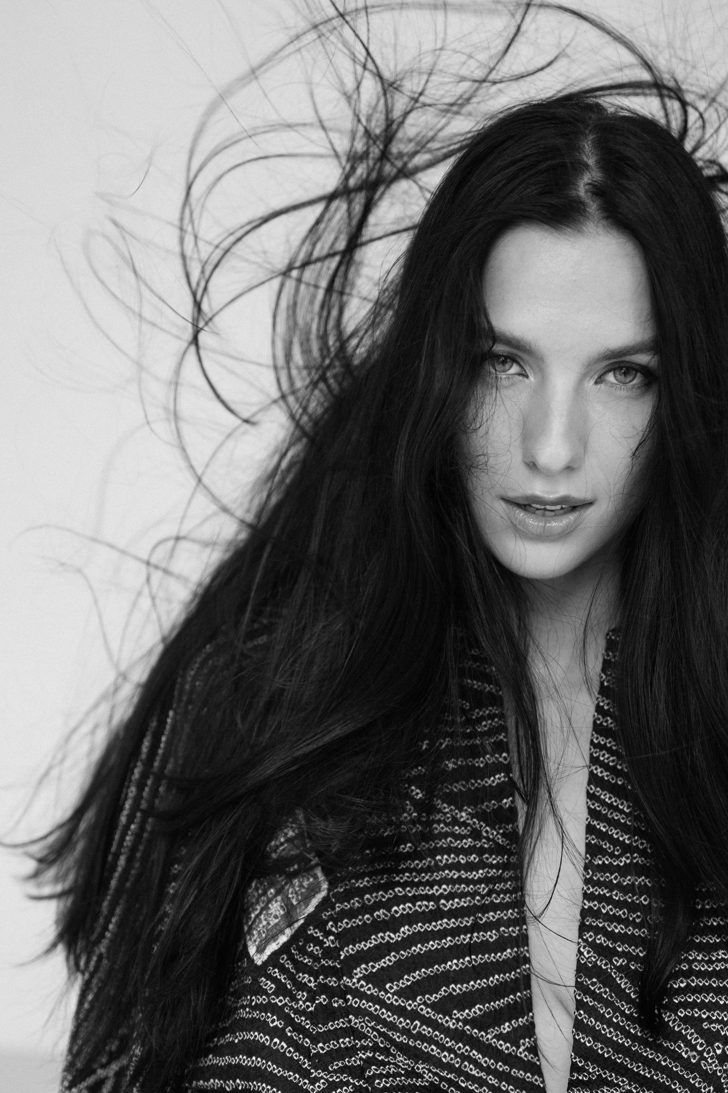 Close-up portrait of woman with long dark hair in black and white.