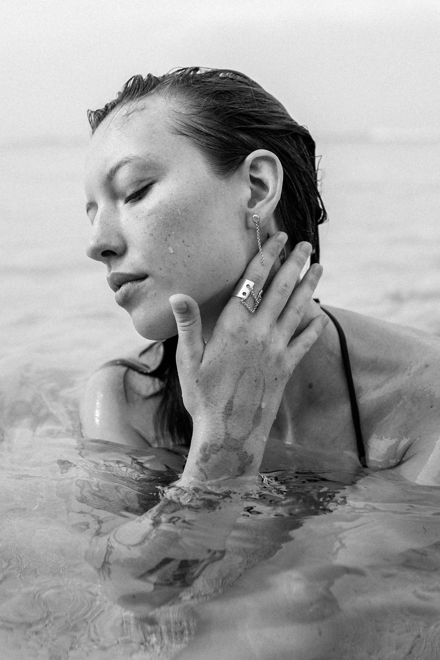 Black and white portrait of woman partially submerged in water with eyes closed.
