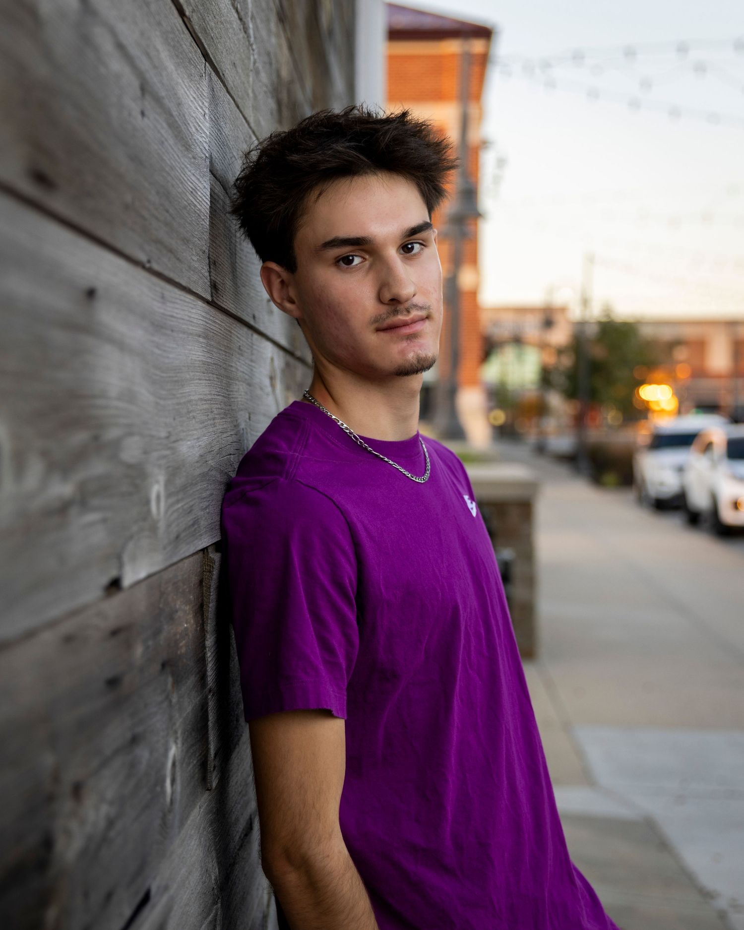 Senior portrait photo of a young man leaning against wall looking at camera at Zona Rosa in KC | Kansas City Northland Portrait Photographer