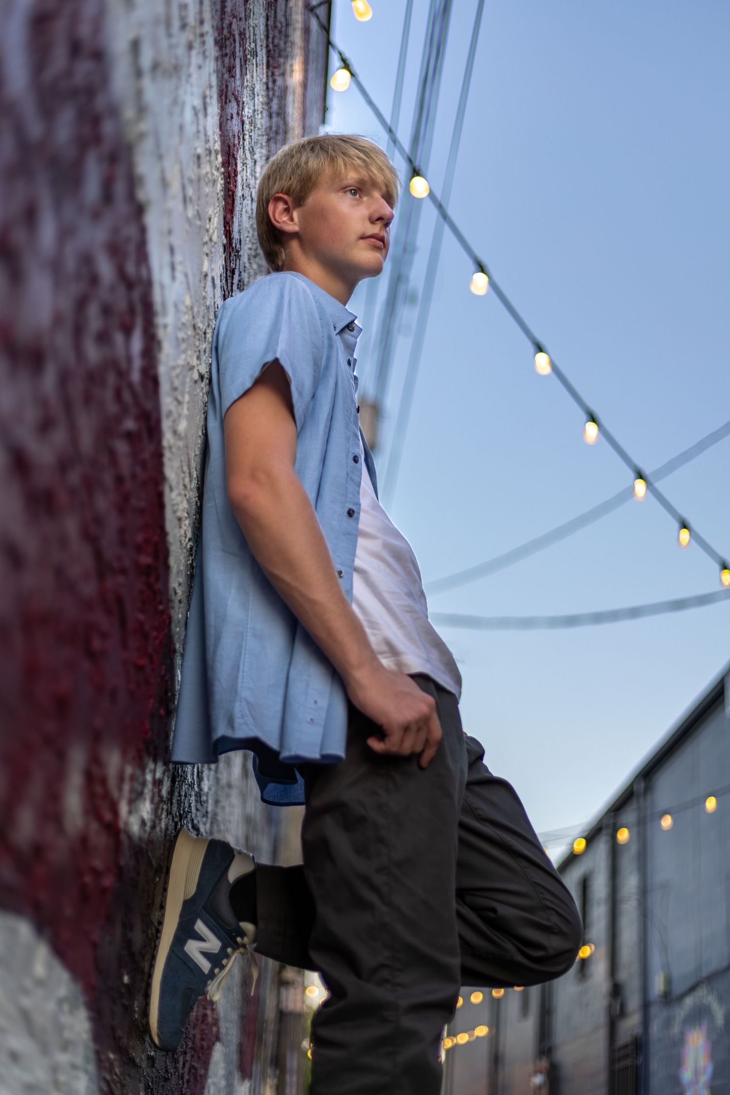 Low angle senior portrait photo of a young man leaning against a wall in Downtown Parkville | Kansas City Northland Portrait Photographer