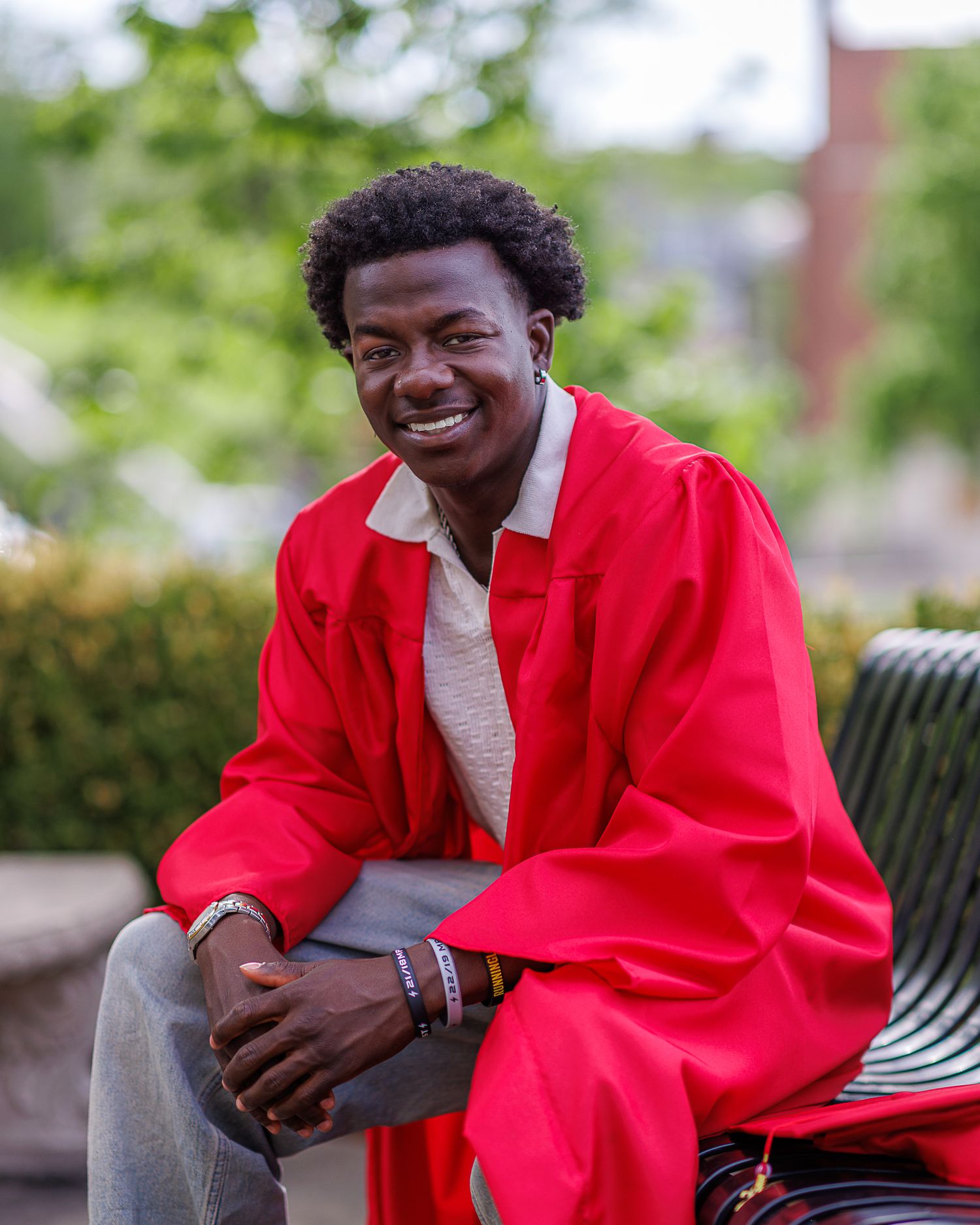 Cap and gown photo of a young man seated on a bench at Park University in Parkville | Kansas City Northland Portrait Photographer