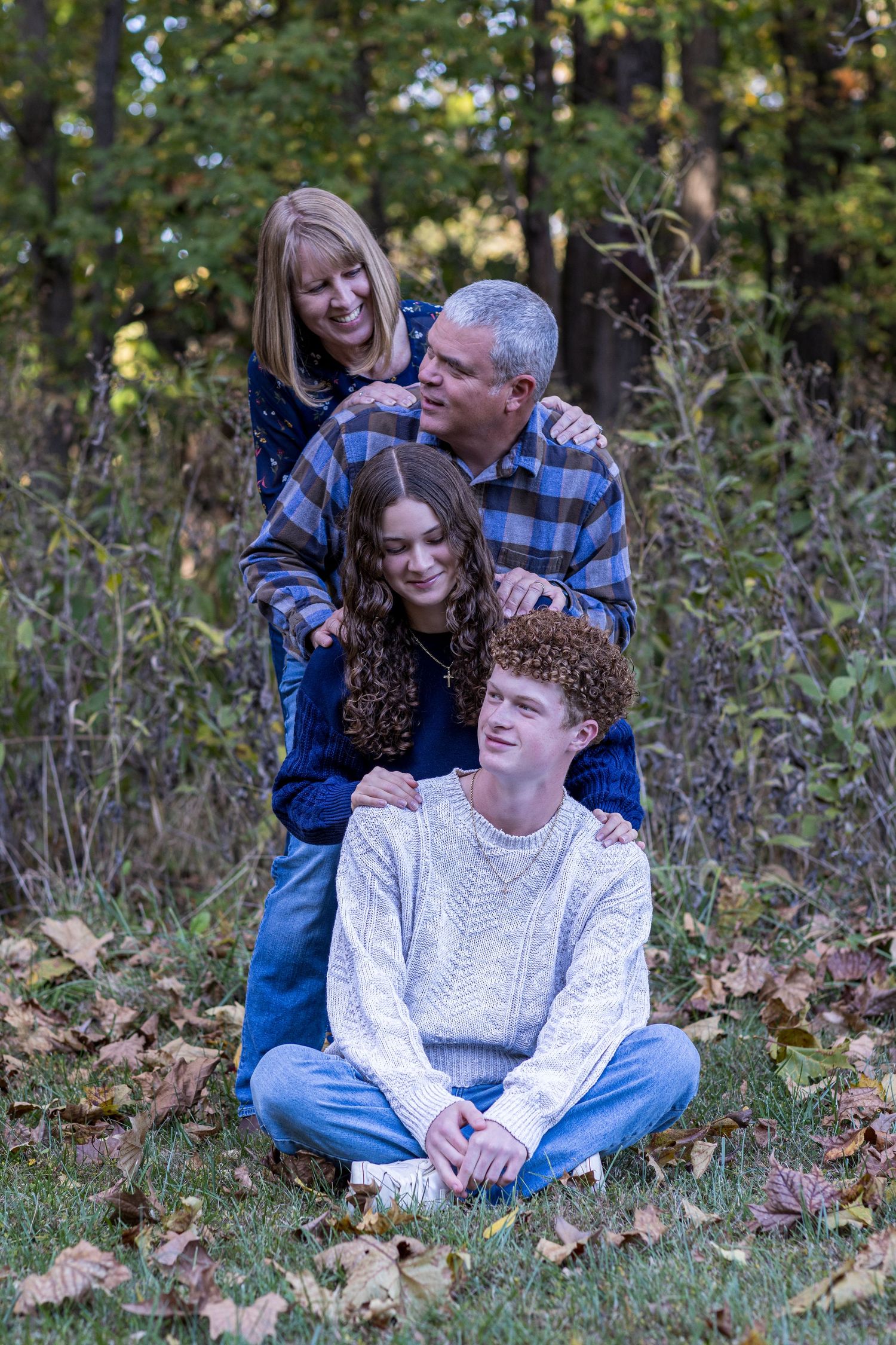 Kansas City portrait photography. Professional photo of family of four doing a silly pose where they are stacked and looking at each other.