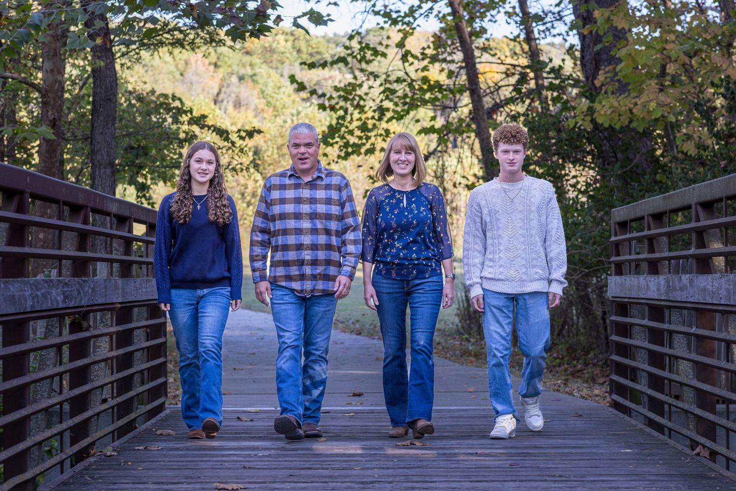 KC portrait photography. Professional backlit of a family smiling and walking across a bridge toward the camera.