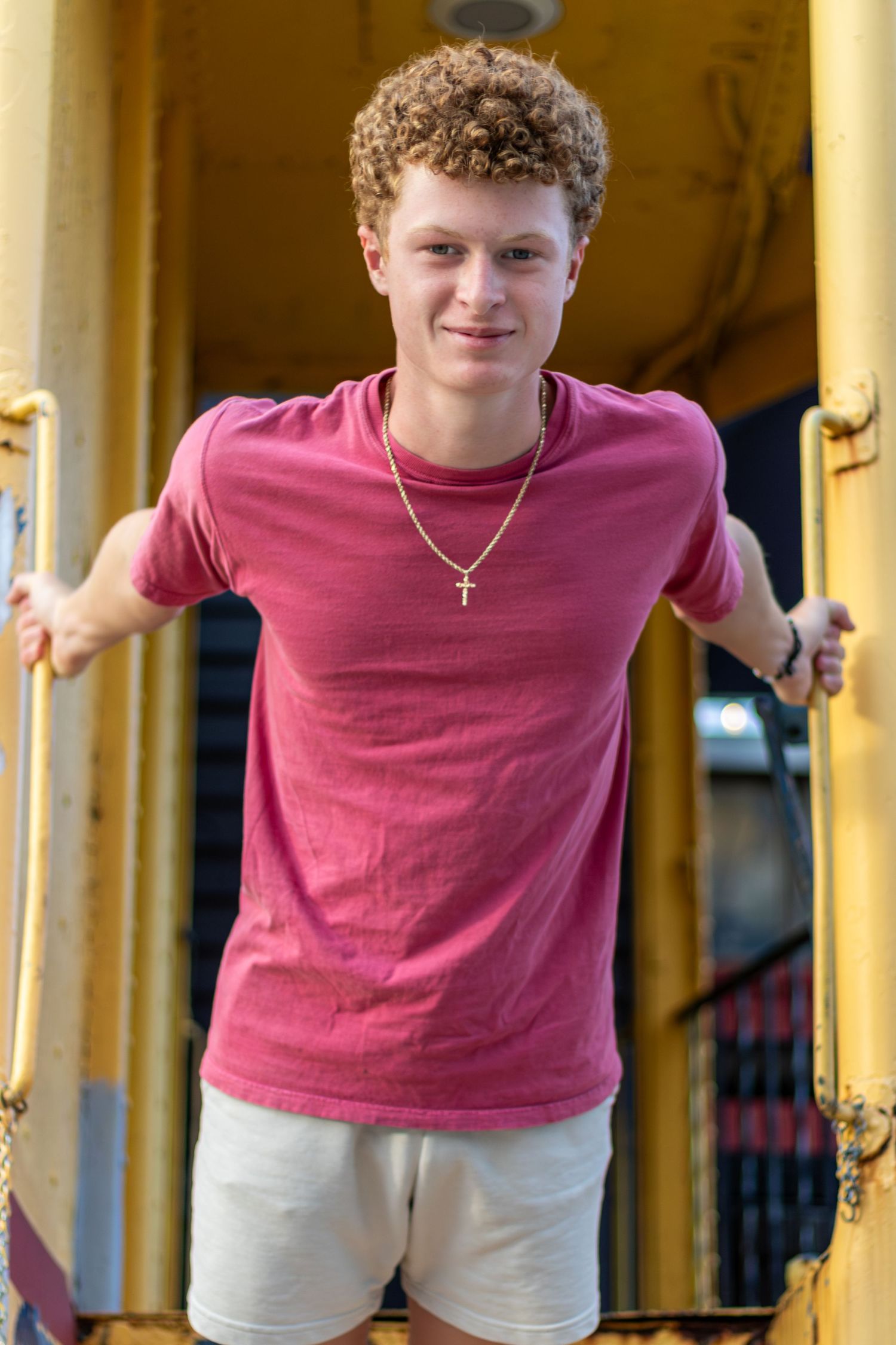 Senior portrait photo of a young man hanging from a train car in Downtown Parkville | Kansas City Northland Portrait Photographer
