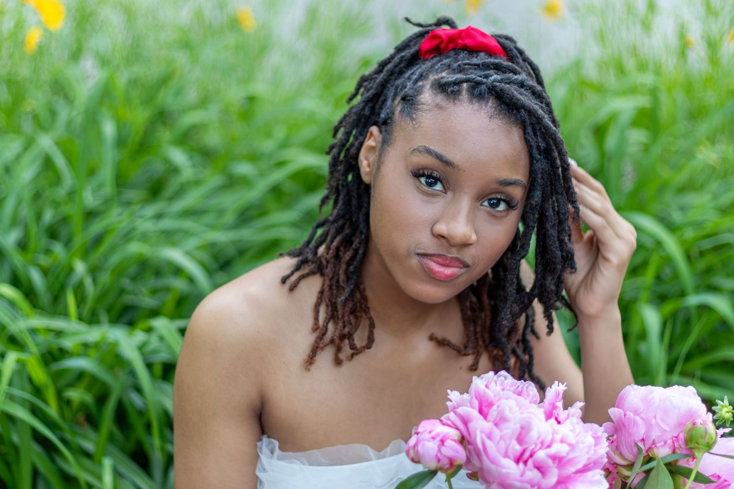 Kansas City portrait photography. Professional senior photo of a young woman smelling flowers and looking at camera.