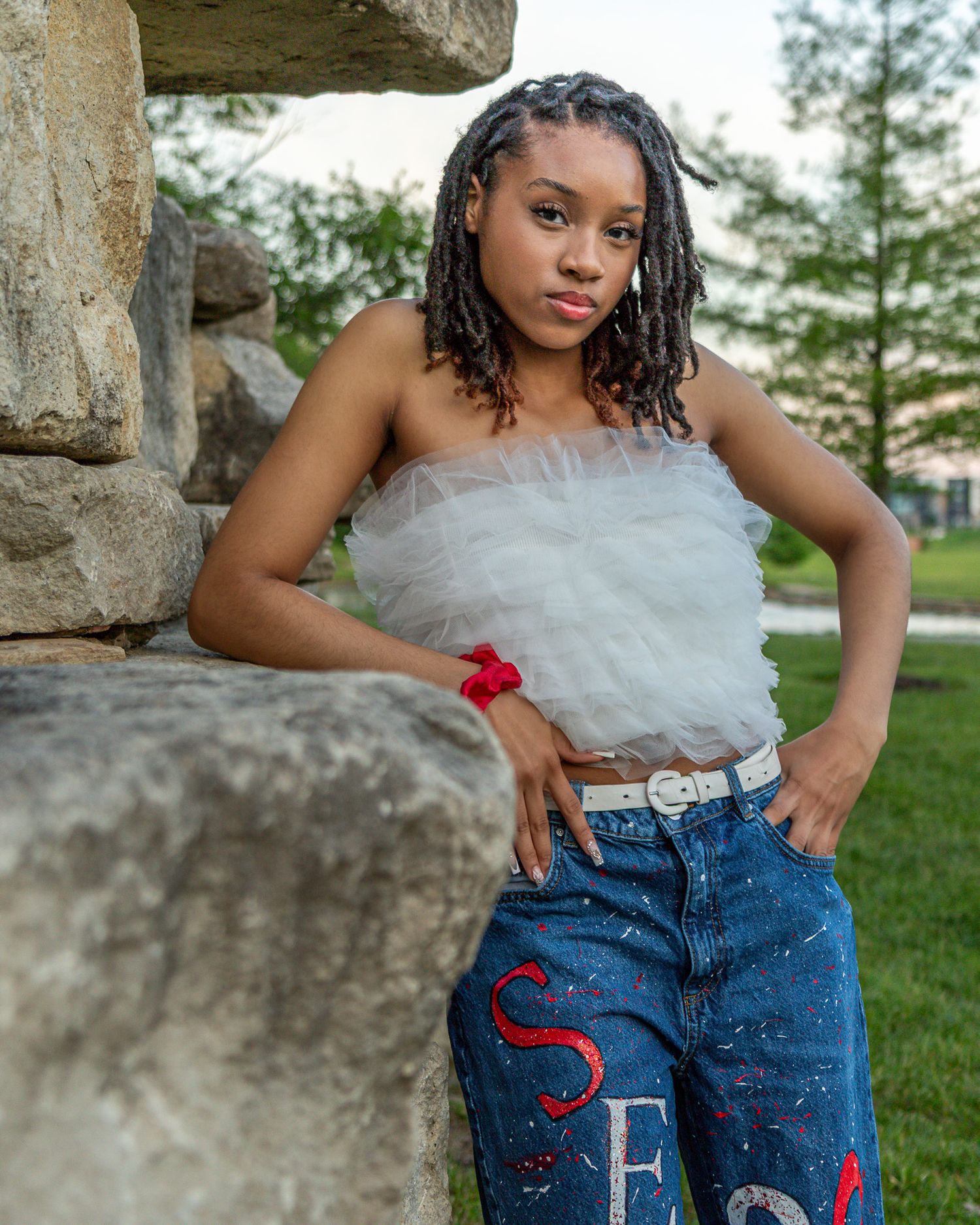 Senior portrait photo of a young lady leaning on rocks near Riverside Waterfall | Kansas City Northland Portrait Photographer
