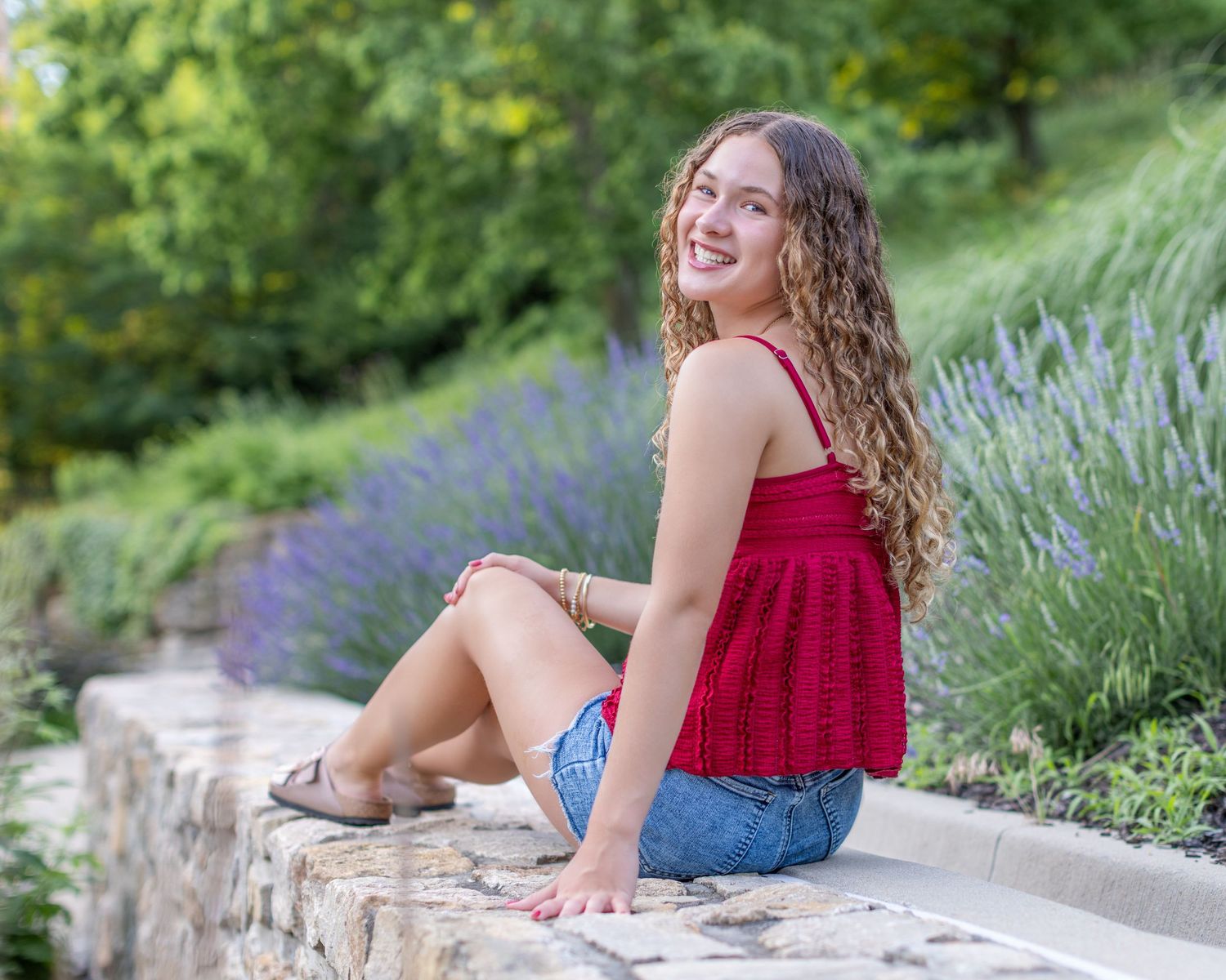 Senior portrait photo of a young lady seated on a rock wall at Park University in Parkville | Kansas City Northland Portrait Photographer