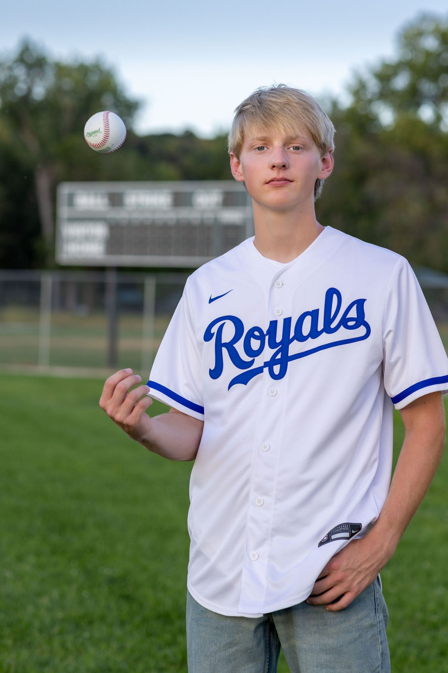 Graduation photo of a young man tossing a baseball at English Landing Park in Parkville | Kansas City Northland Portrait Photographer