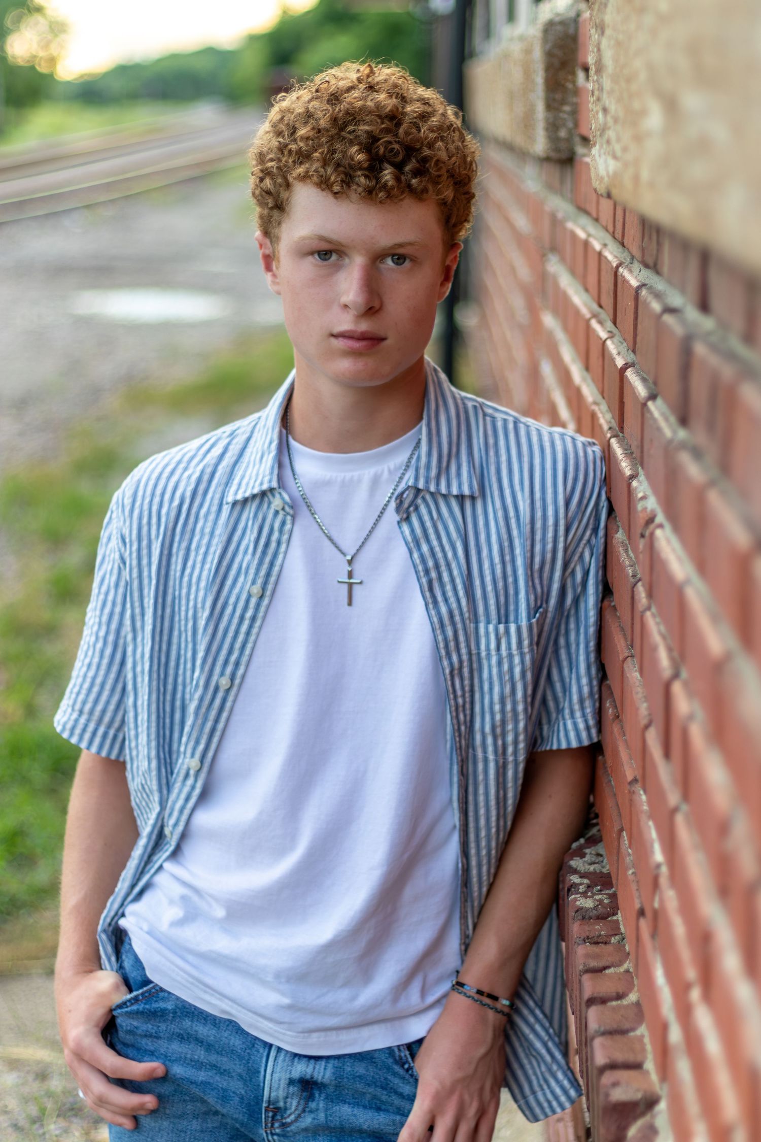 Graduation photo of a young man leaning against a brick wall in Downtown Parkville | Kansas City Northland Portrait Photographer