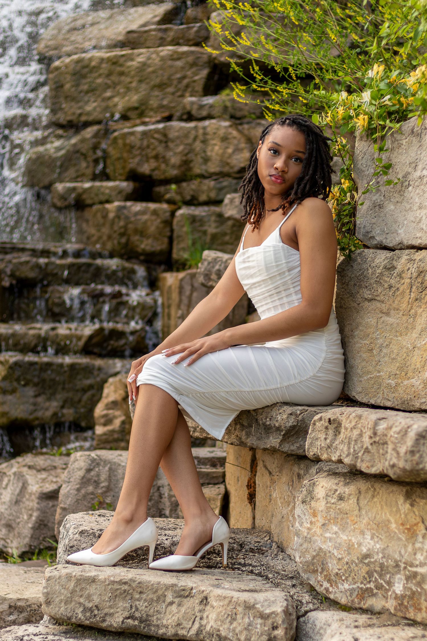 Senior portrait of a young lady sitting on the rocks at the Riverside waterfall | Kansas City Northland Portrait Photographer