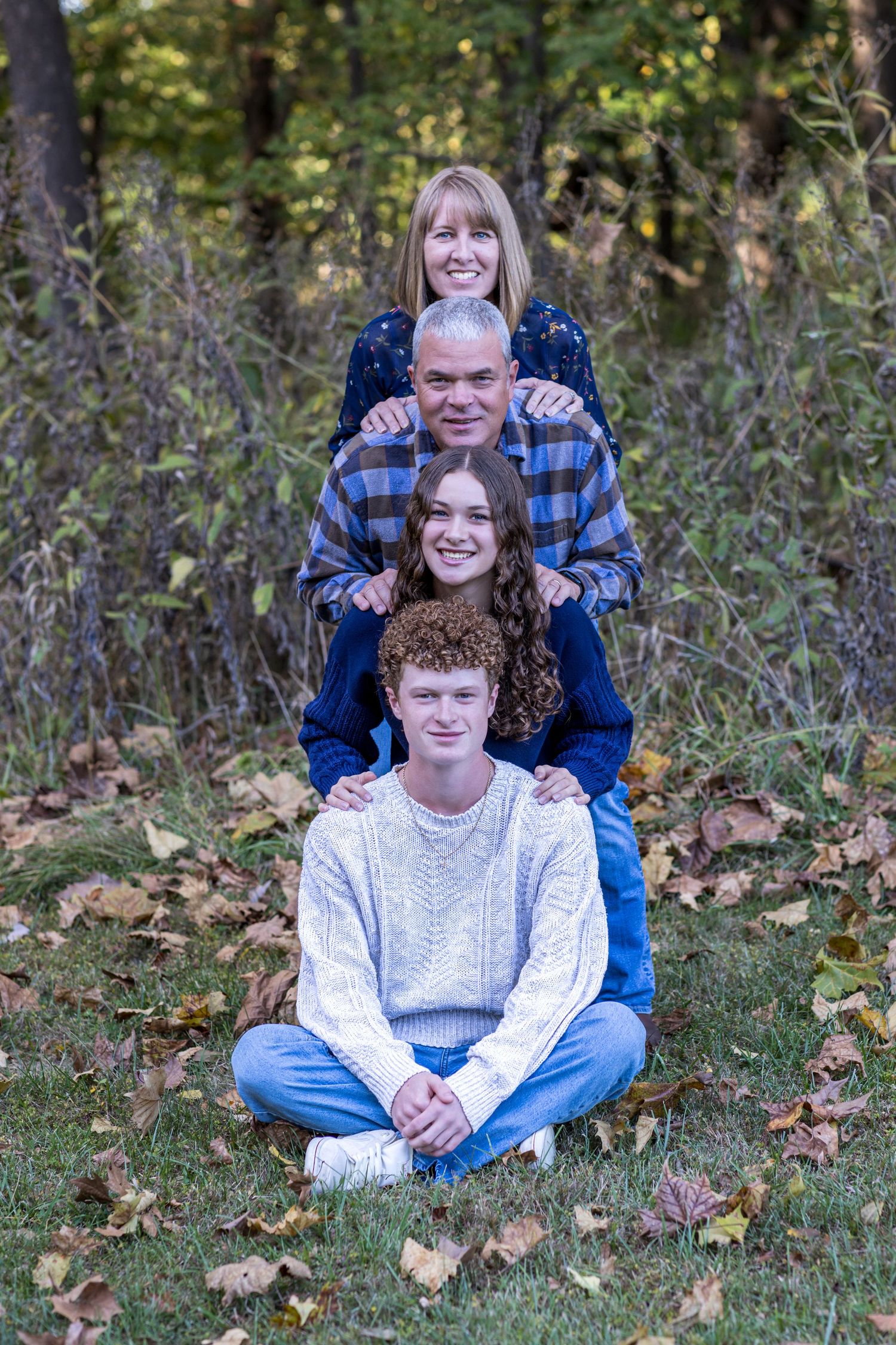 Kansas City portrait photography. Professional photo of a family of four in a park setting forming a tower of smiles.