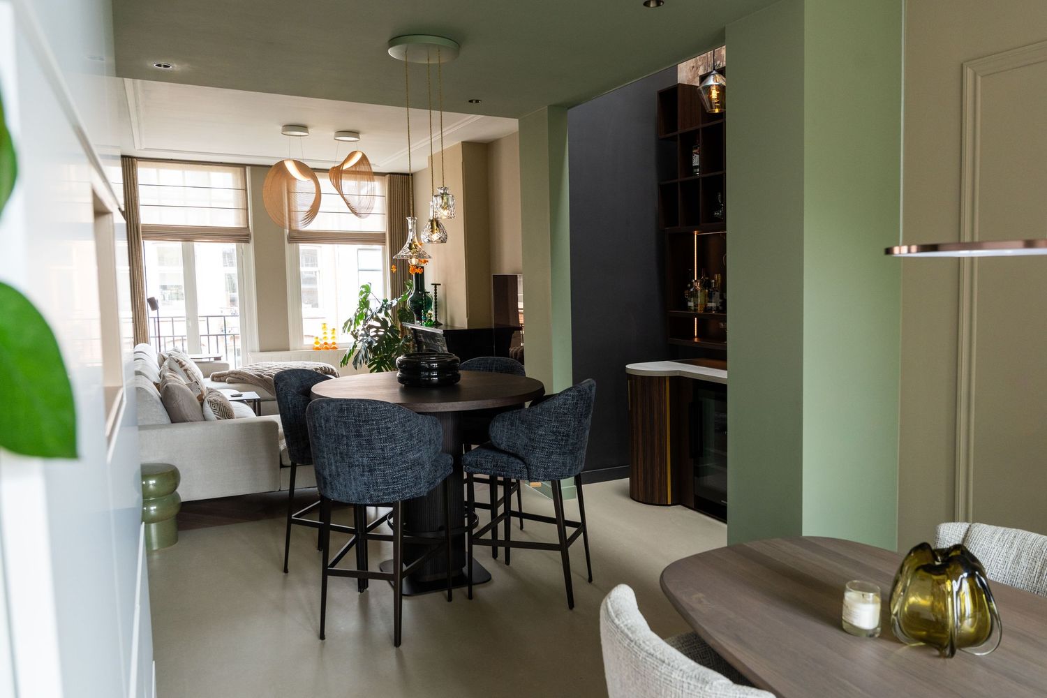 Modern apartment interior with green walls features an open concept living space and minimalist decor throughout.