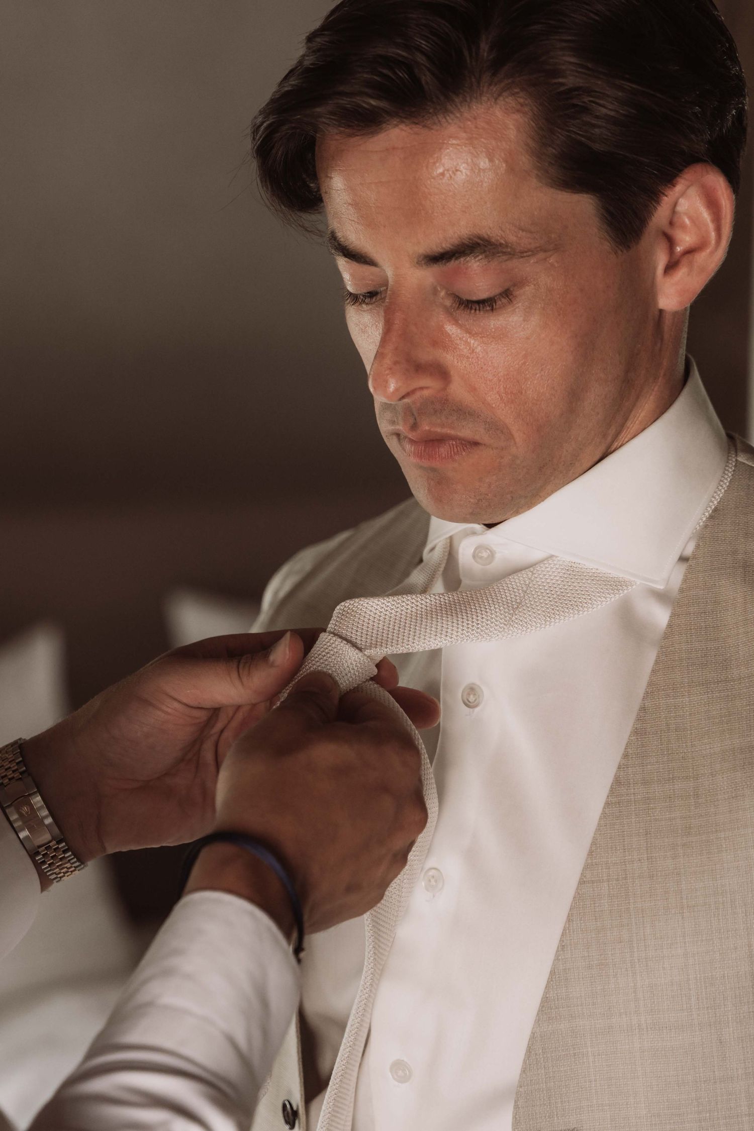 Close-up sequence of someone adjusting a white dress shirt collar and tie for a formal occasion.