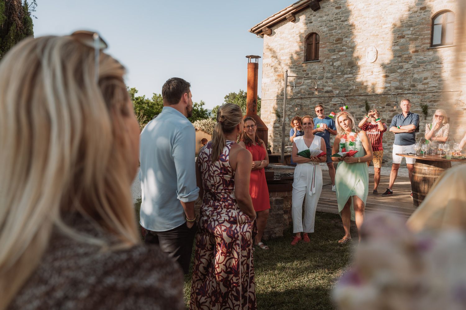 Wedding guests mingle and socialize during an outdoor cocktail hour at a rustic stone venue during golden hour.