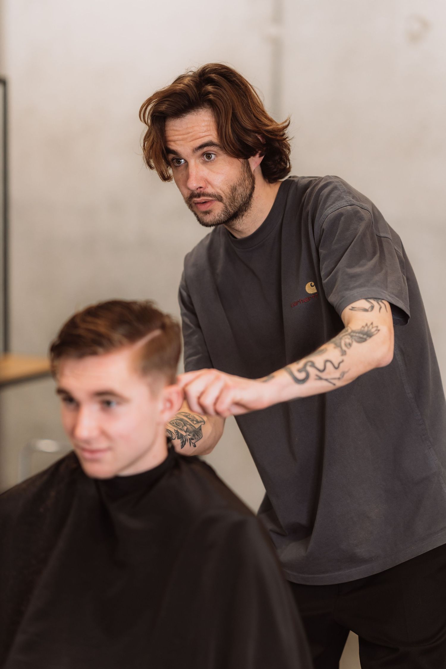 Hair stylist in dark clothing providing a precision haircut service.