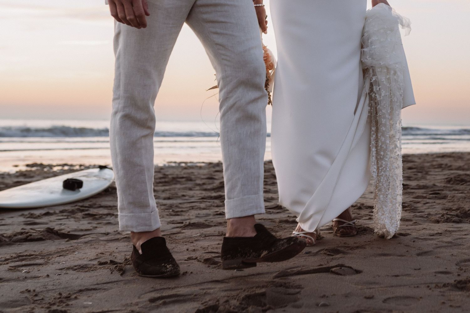 Close-up of feet walking in the sand during a beach wedding photoshoot.