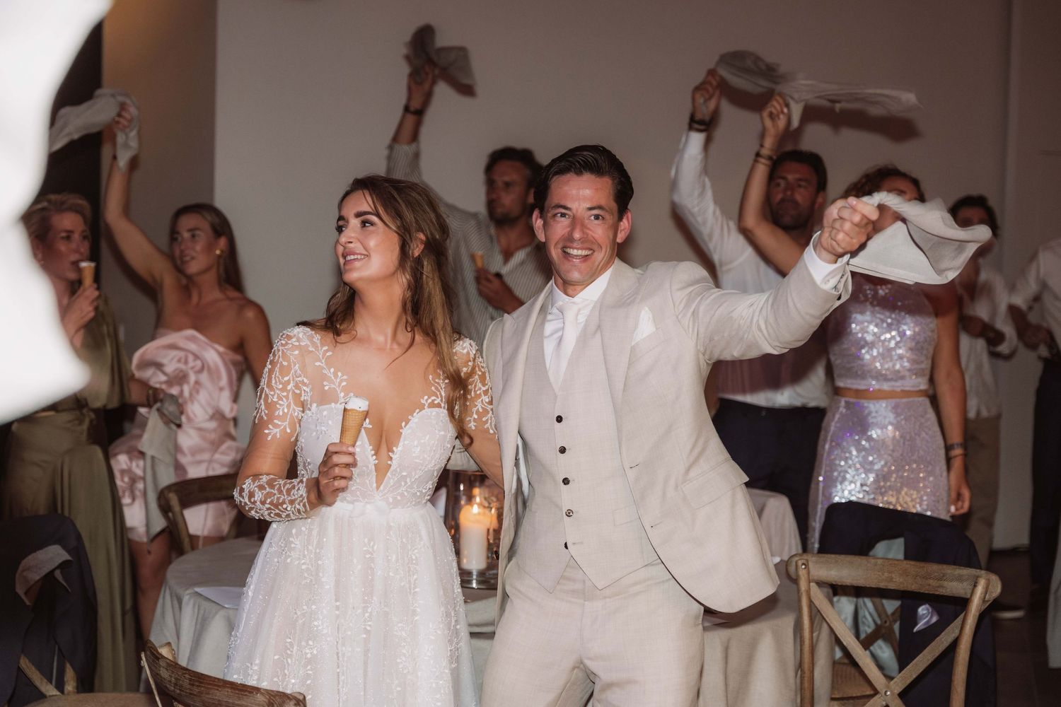 People in white outfits dancing and celebrating at what appears to be a wedding reception or party.