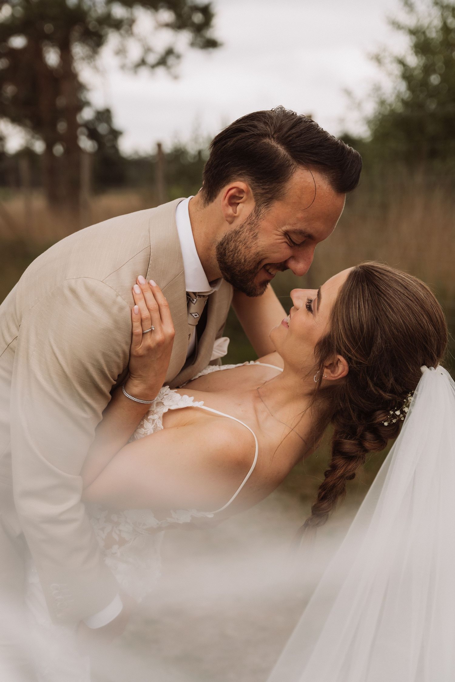 Romantic wedding couple shares an intimate kiss in a dreamy outdoor setting.