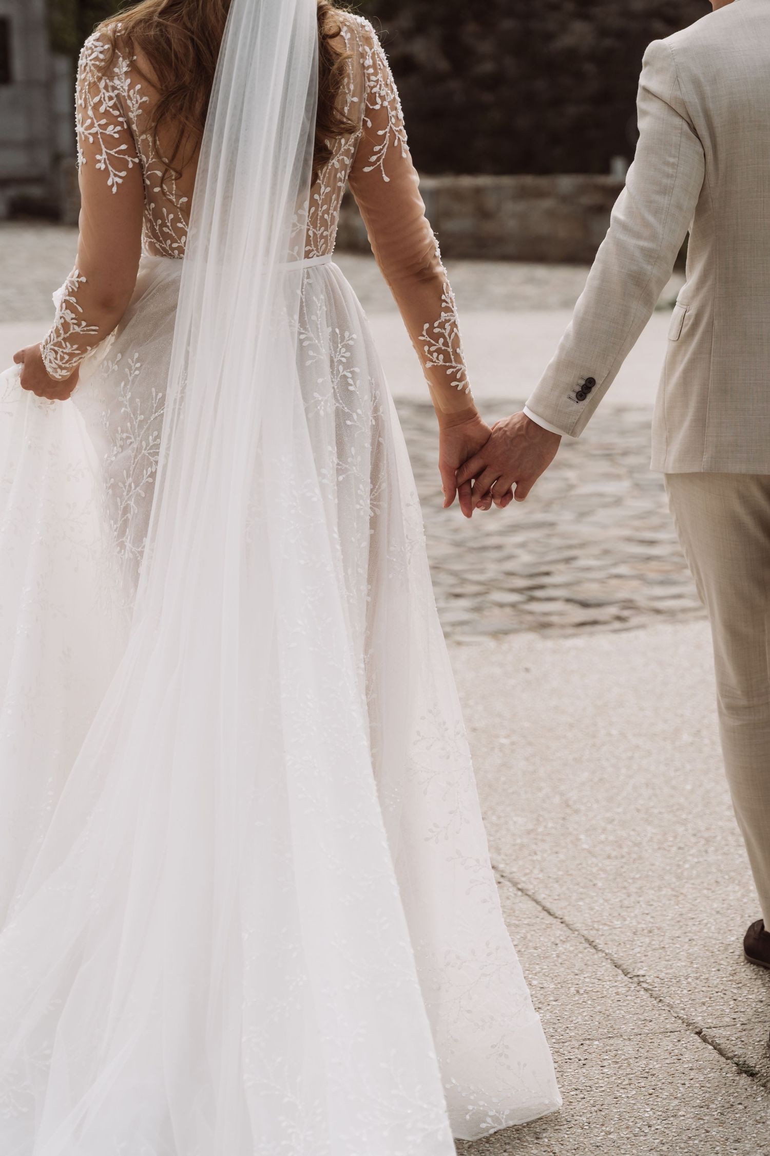 Side view of an elegant wedding dress with sheer lace details and flowing train.