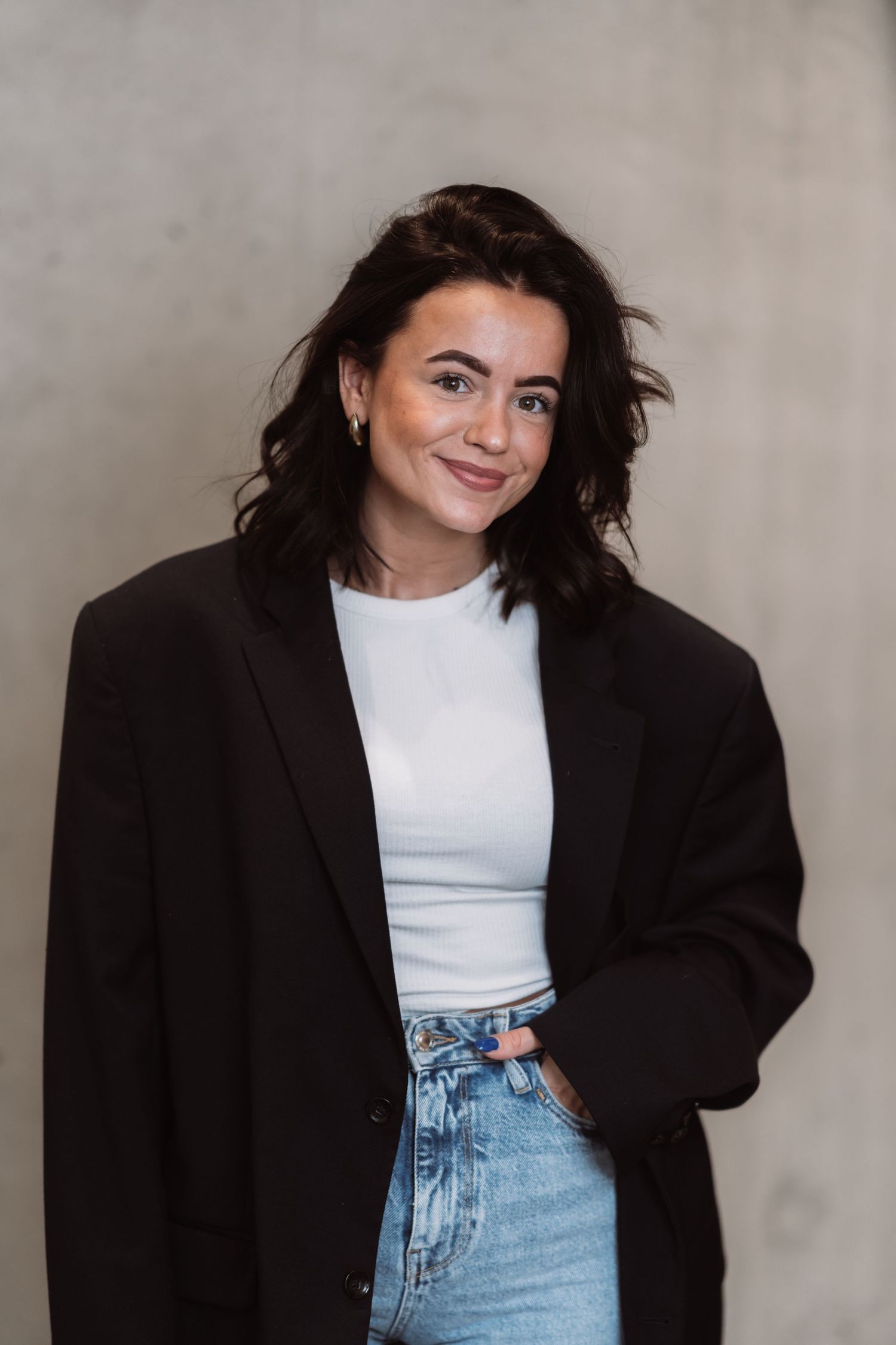 Fashion portrait of person wearing oversized black blazer with white top and jeans.