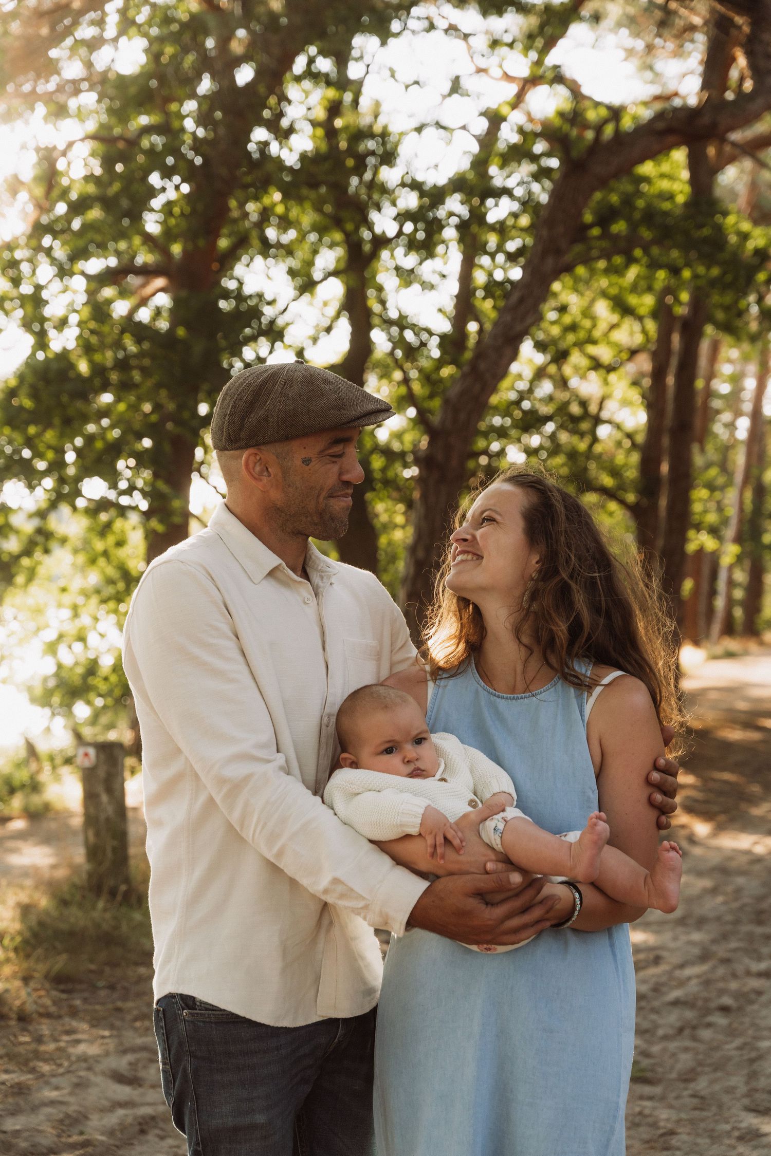 Family enjoying a tender moment together in a sunlit wooded area.