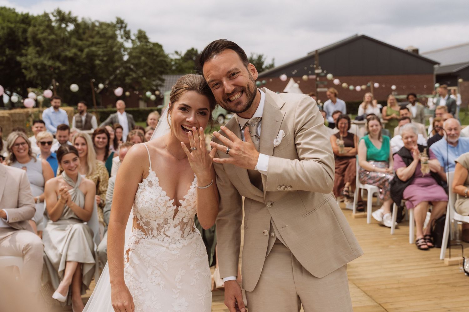 Wedding ceremony on an outdoor wooden deck with guests seated under cloudy skies.