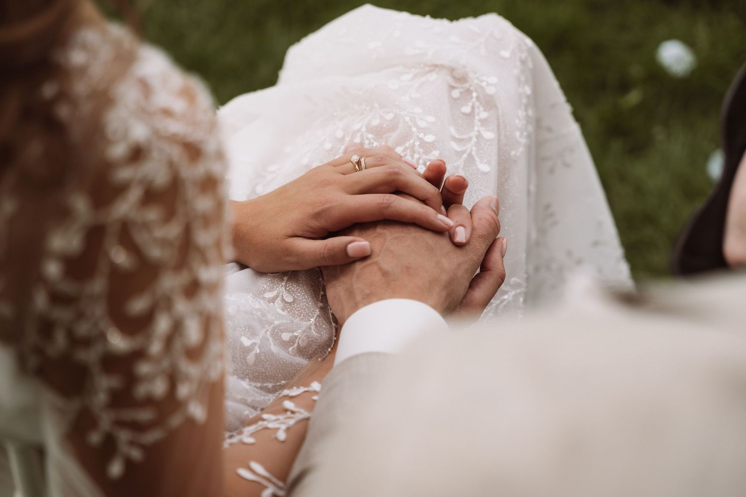 Close-up detail of hands exchanging wedding rings during an intimate ceremony.