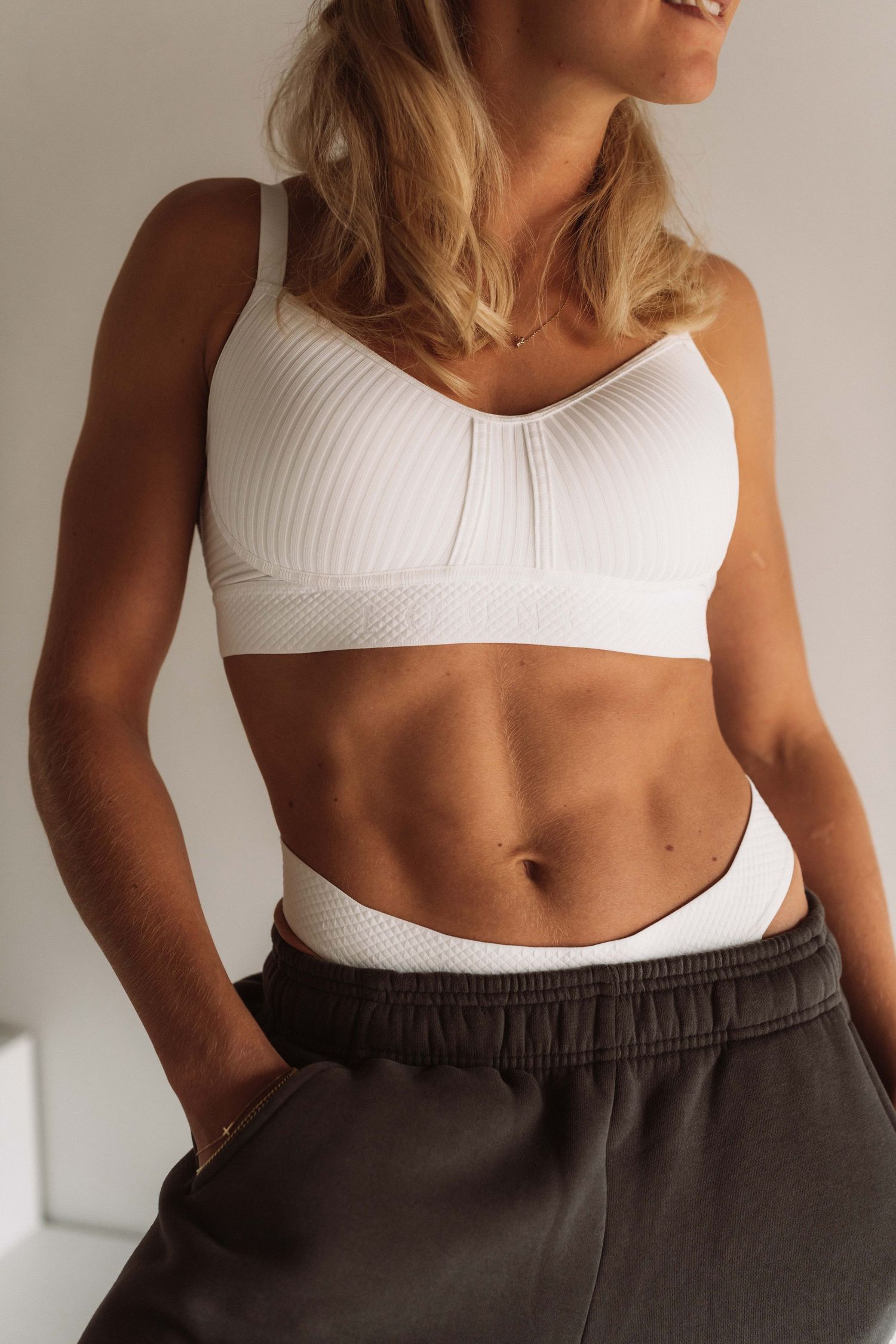 Person wearing white athletic top and dark sweatpants showing fitness style.