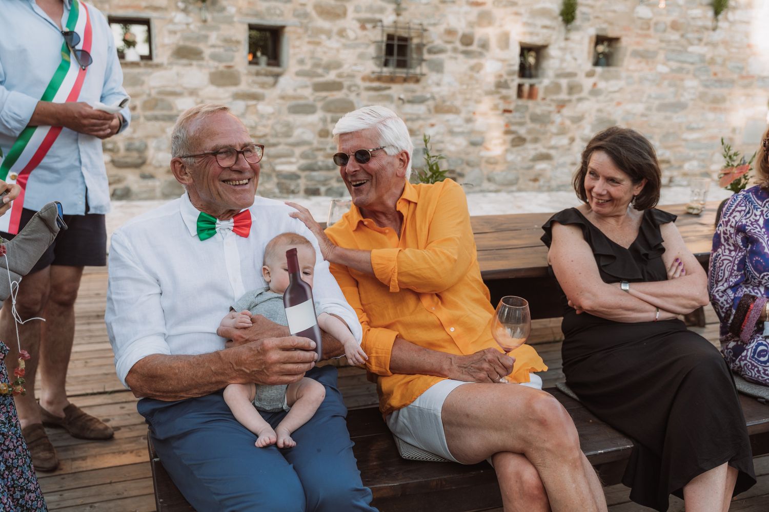 Group of people enjoying conversation and laughter while sitting together on outdoor patio furniture.