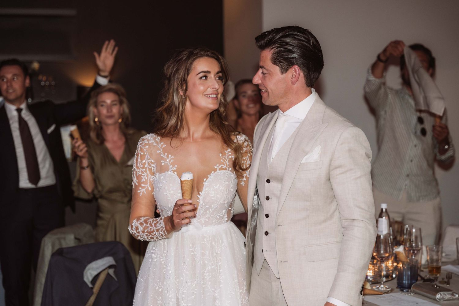 Wedding reception guests in white attire dance and celebrate on an elegant candlelit dance floor.
