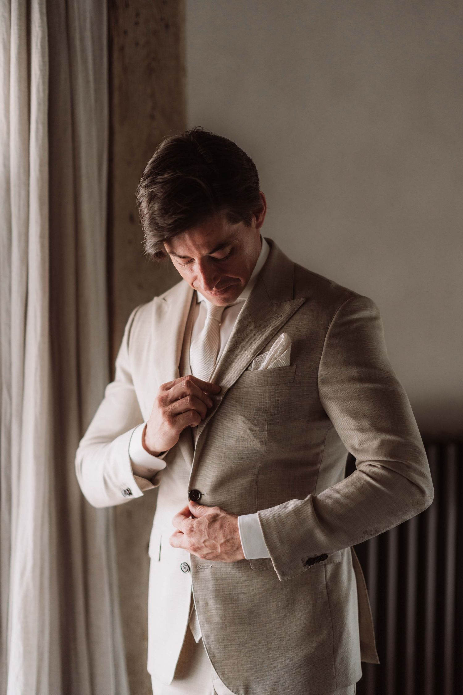 Series of emotional portraits showing someone in a light colored suit adjusting their tie and covering their face.