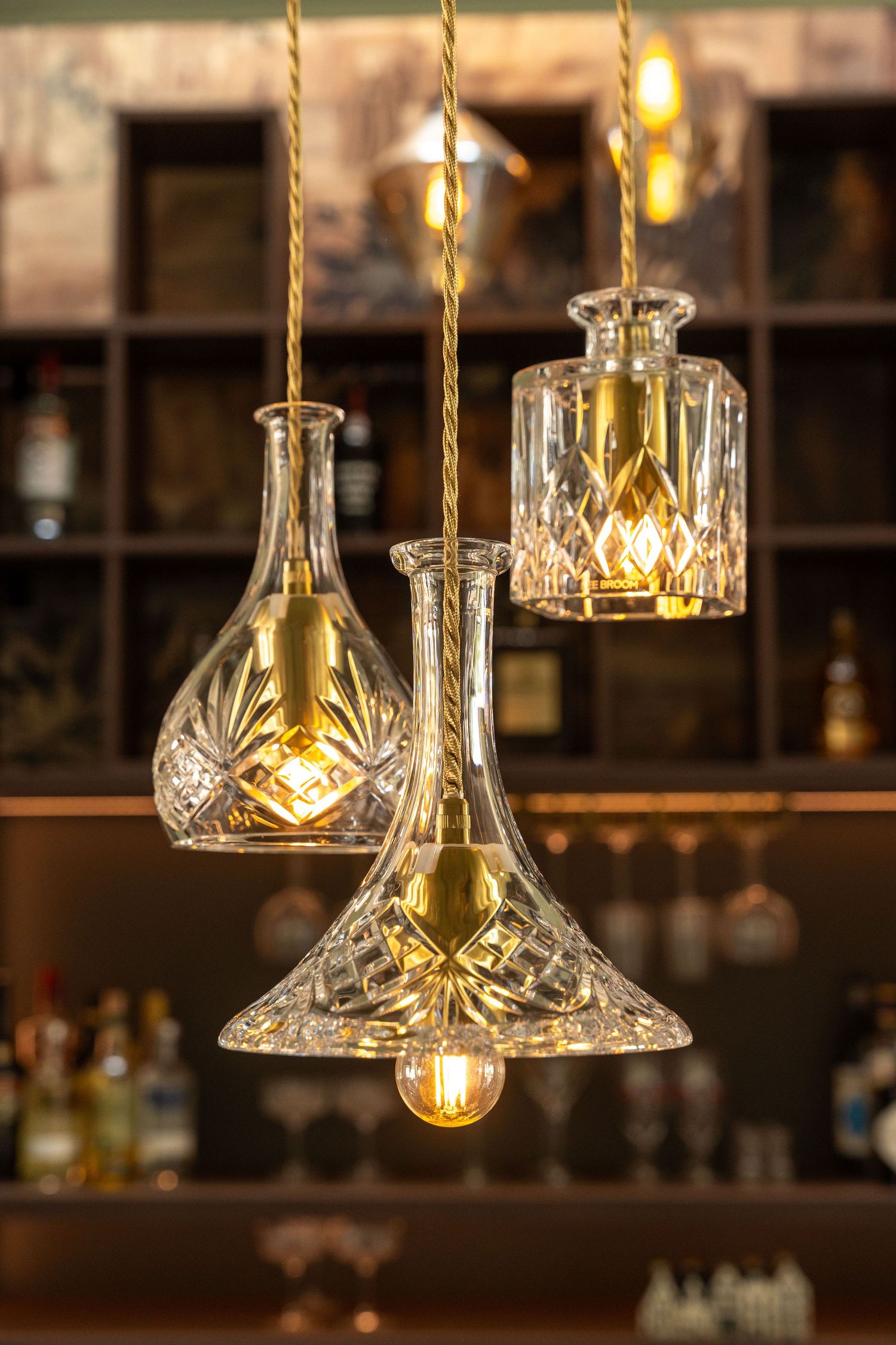 Crystal pendant lights with gold accents hang from ropes creating an elegant bar ambiance.