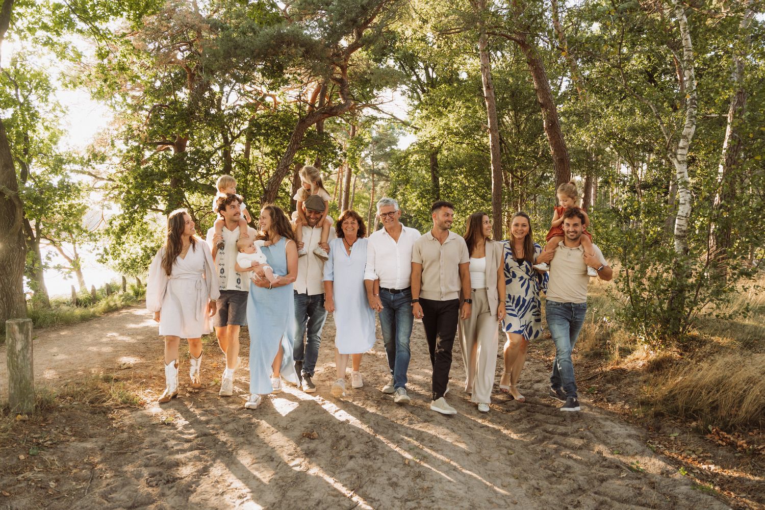 Large group walking together on a forest path during golden hour.