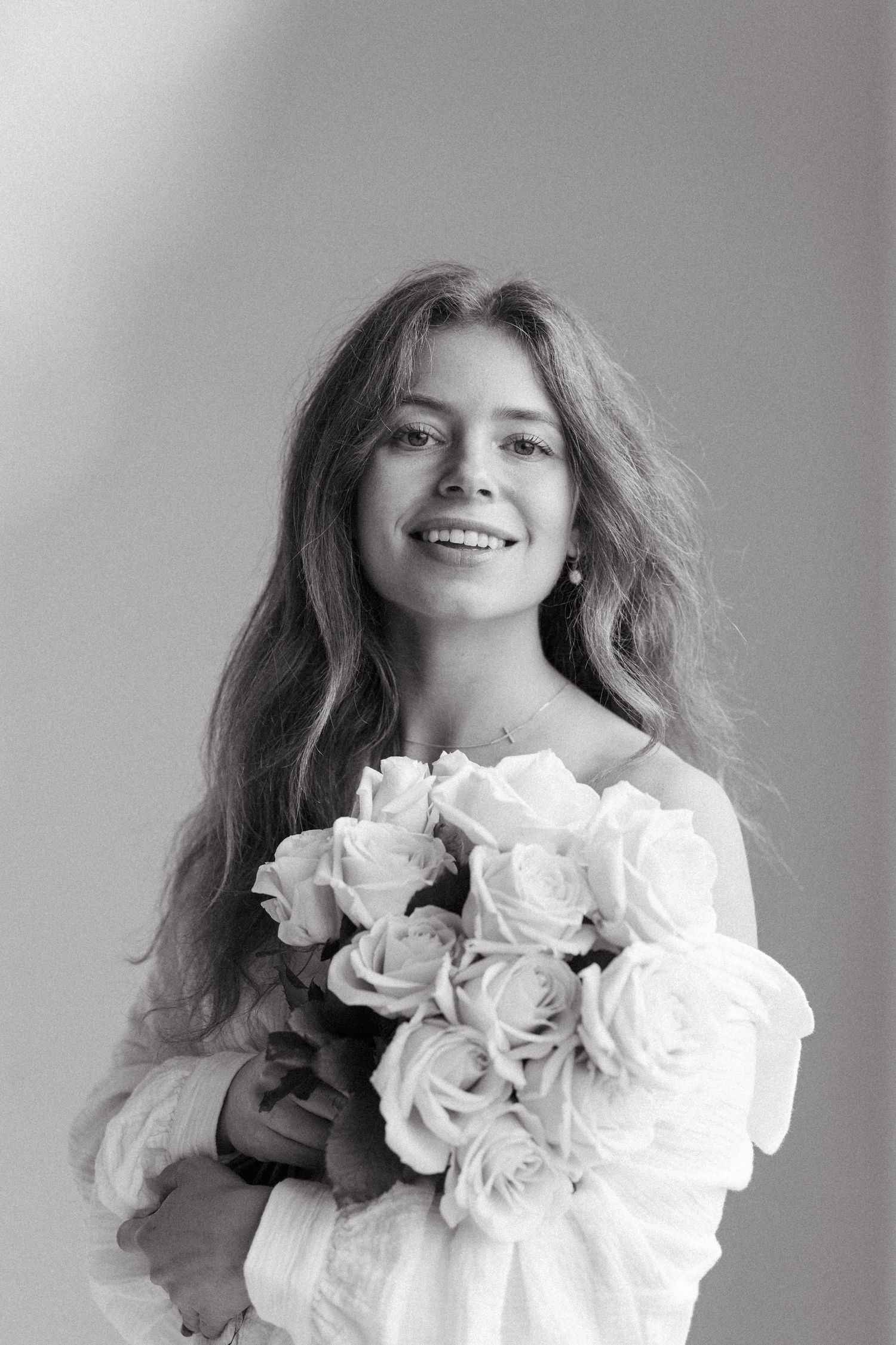 A black and white photo series shows someone posing with a bouquet of white roses against a simple backdrop.