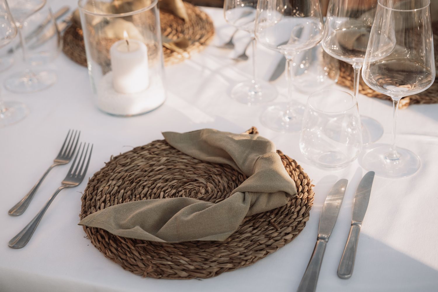 Elegant table settings with woven placemats, white napkins, and wine glasses create an upscale dining atmosphere.